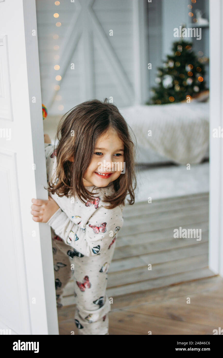 Poco felice bruna ragazza in intimo pigiami guarda dal lettino per bambini  camera, tempo di Natale Foto stock - Alamy