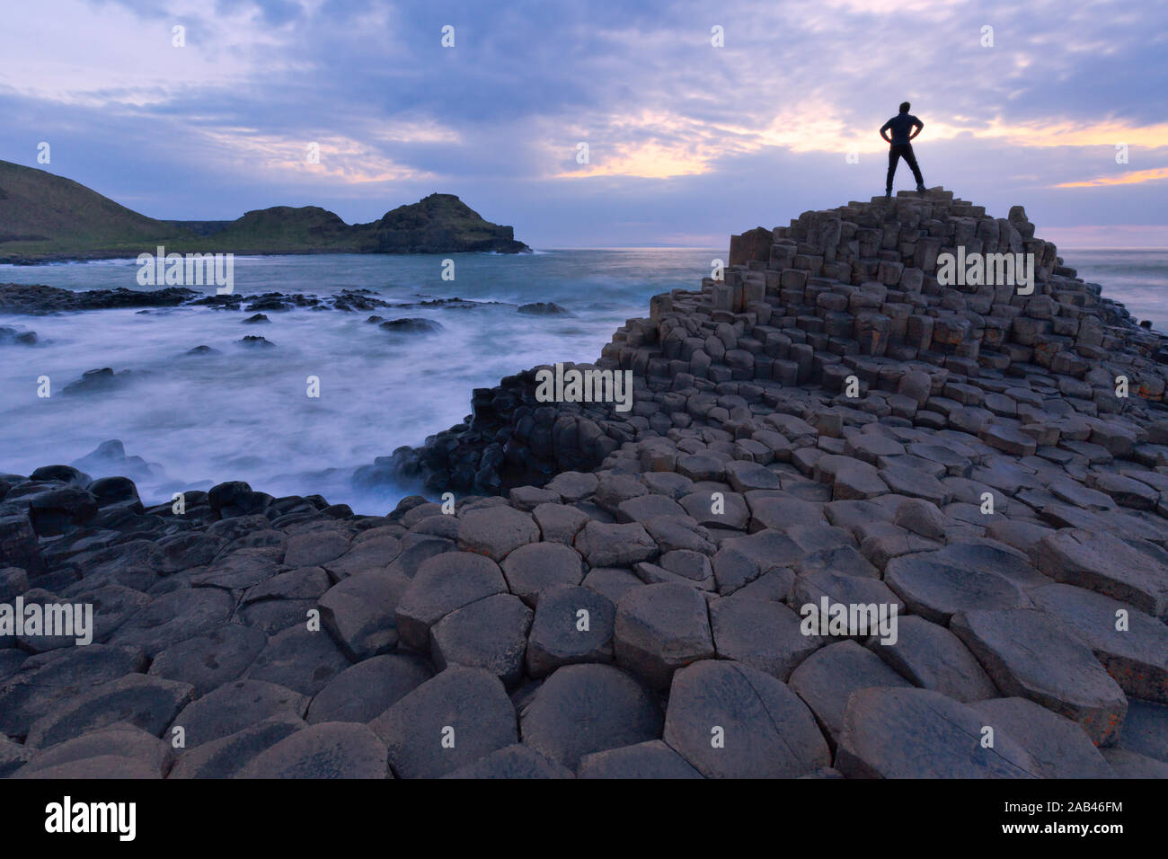 Silhouette di una persona in piedi al Giant Causeway rocce al tramonto in Irlanda del Nord Foto Stock