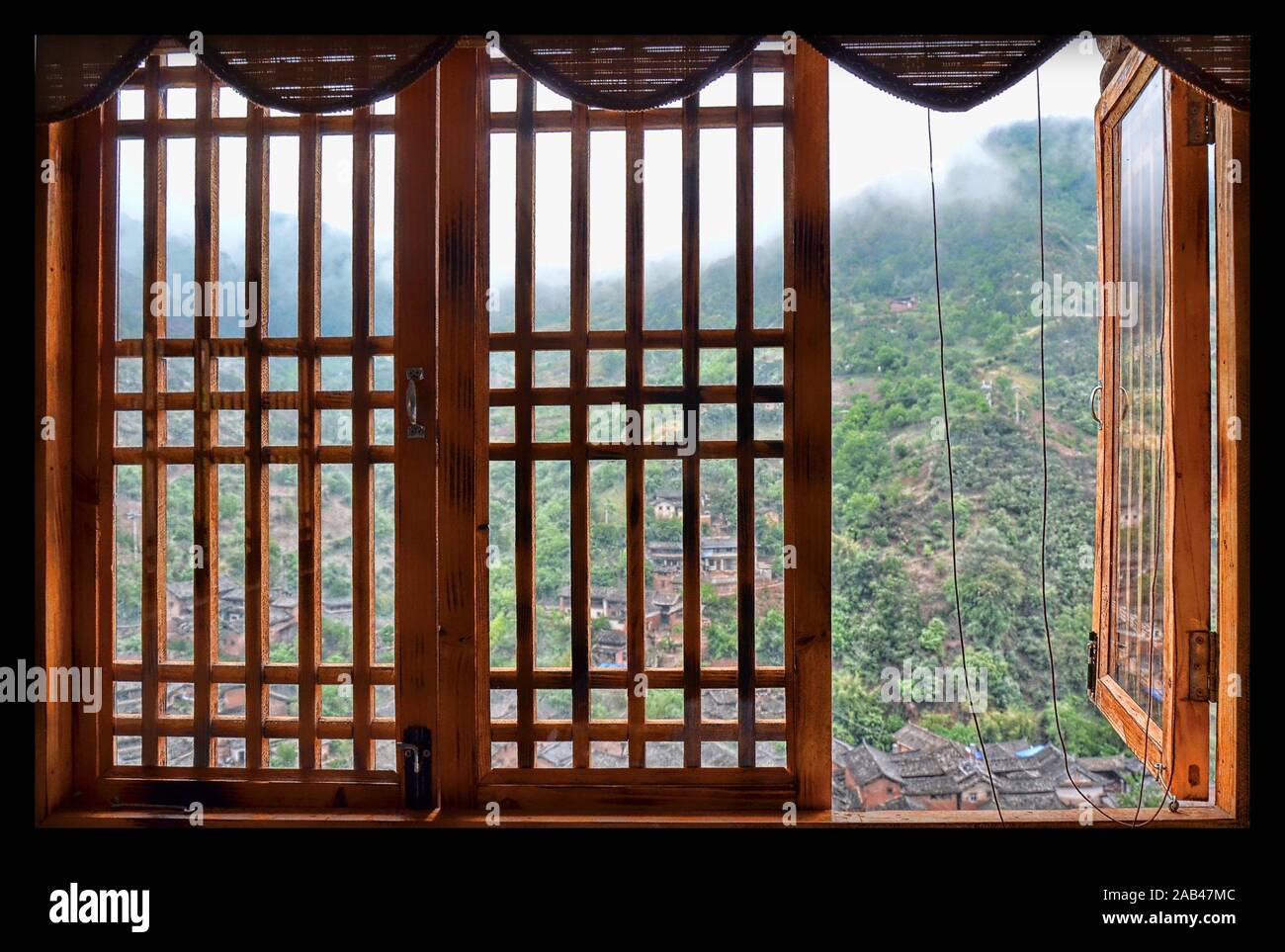 Finestra aperta nel villaggio di Nuodeng, provincia di Yunnan, Cina. Nebbia mattutina in montagna. Foto Stock