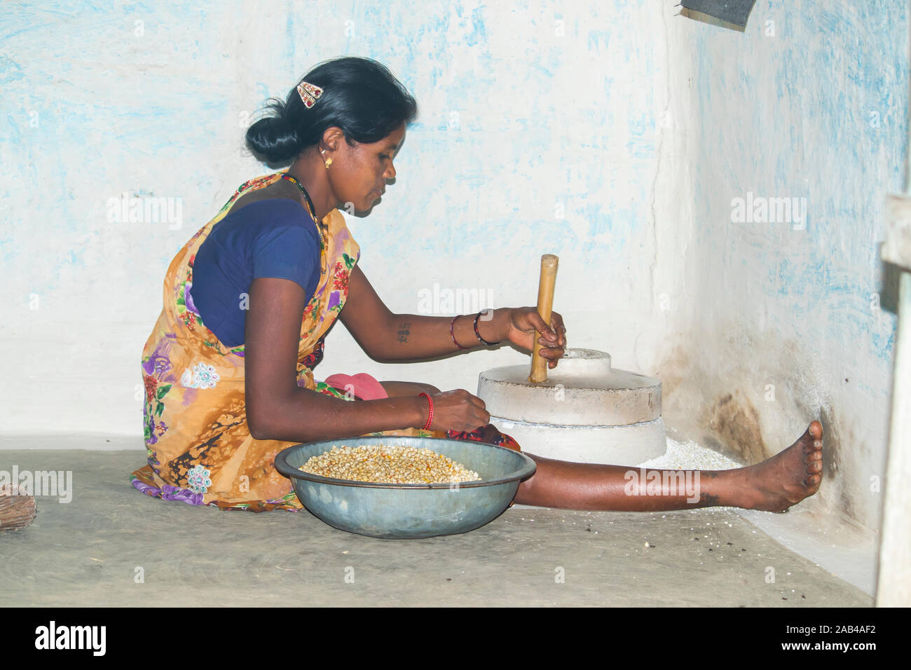 Sijhora, Madhya Pradesh, India- Novembre 2019 : rurale donna indiana utilizzare mani mulino per la macina del mais in Sijhora Madhya Pradesh India. Foto Stock