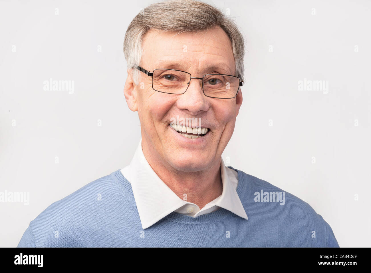 Ritratto di Felice uomo anziano che posano su grigio di sfondo per studio Foto Stock