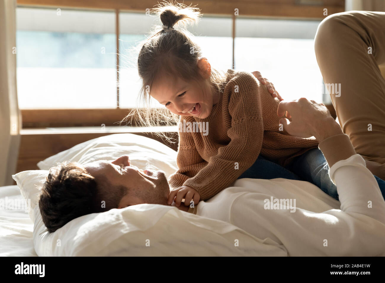 Carino kid figlia giocando con il papà su letto di mattina Foto Stock