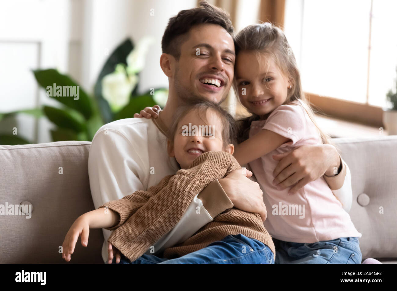 Caring daddy e simpatici ragazzi ragazze abbracci di incollaggio sul divano Foto Stock