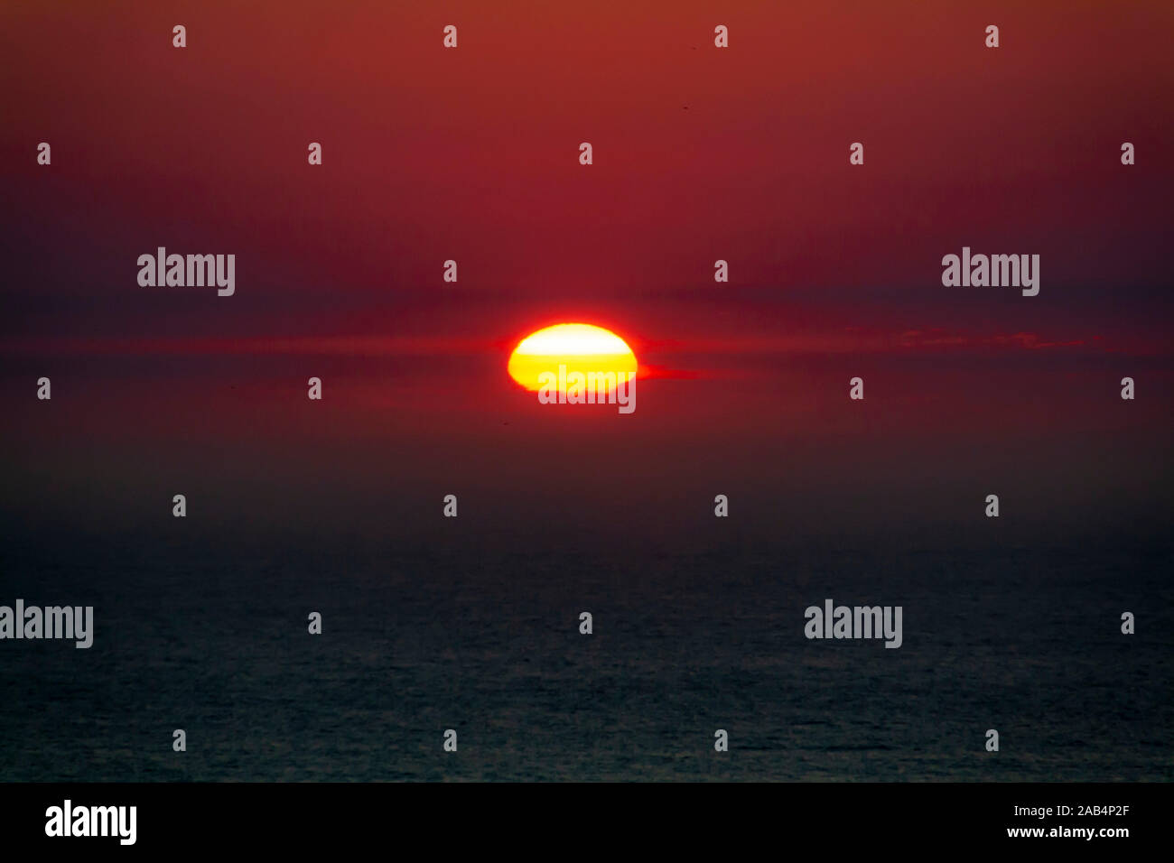 Mezza sun sunset vista orizzonte nel cielo rosso Foto Stock