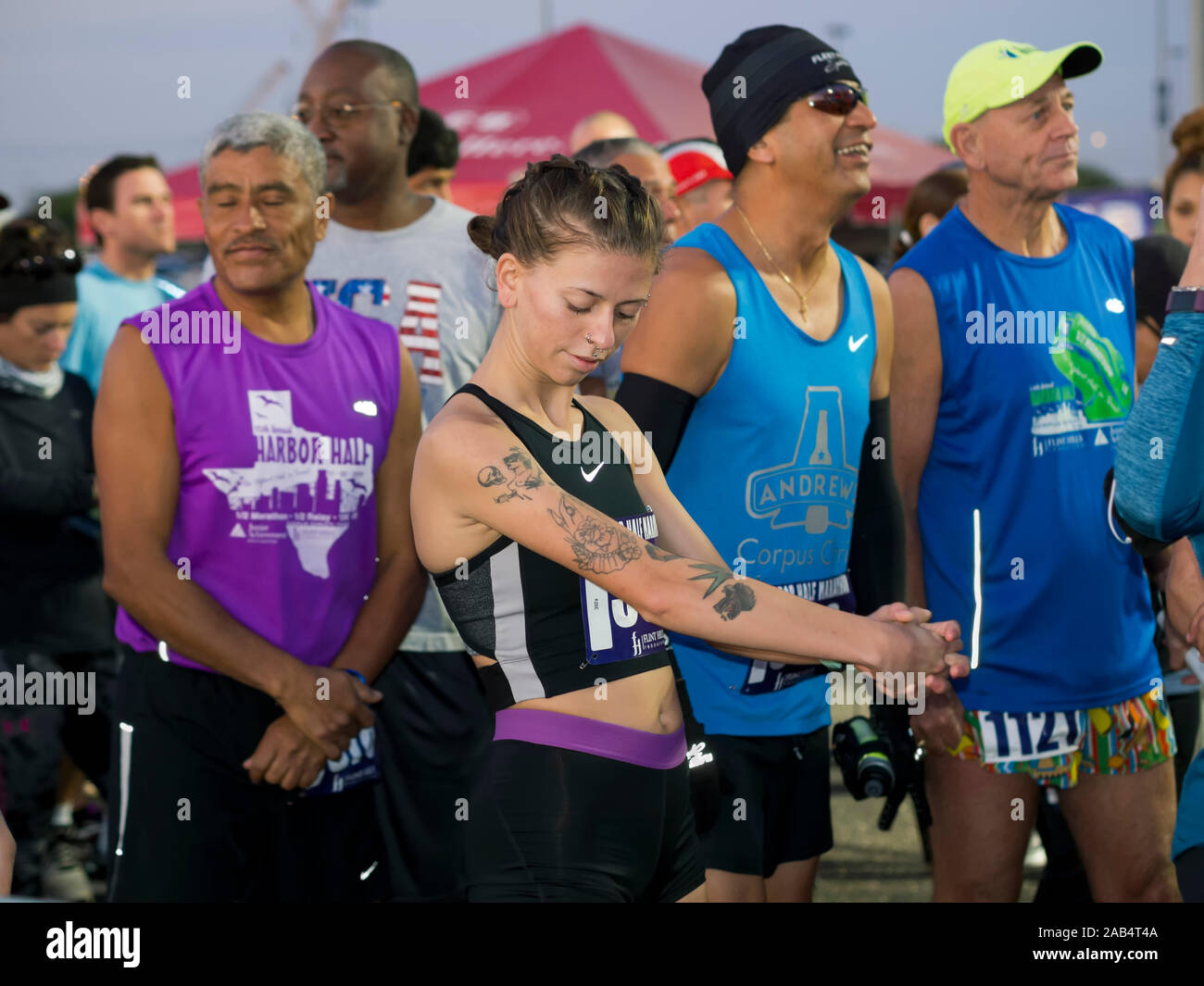 Tatuato donna caucasica e altri concorrenti attendono la mattina presto inizio del Corpus Christi, Texas USA XV Porto annuale Mezza Maratona. Foto Stock