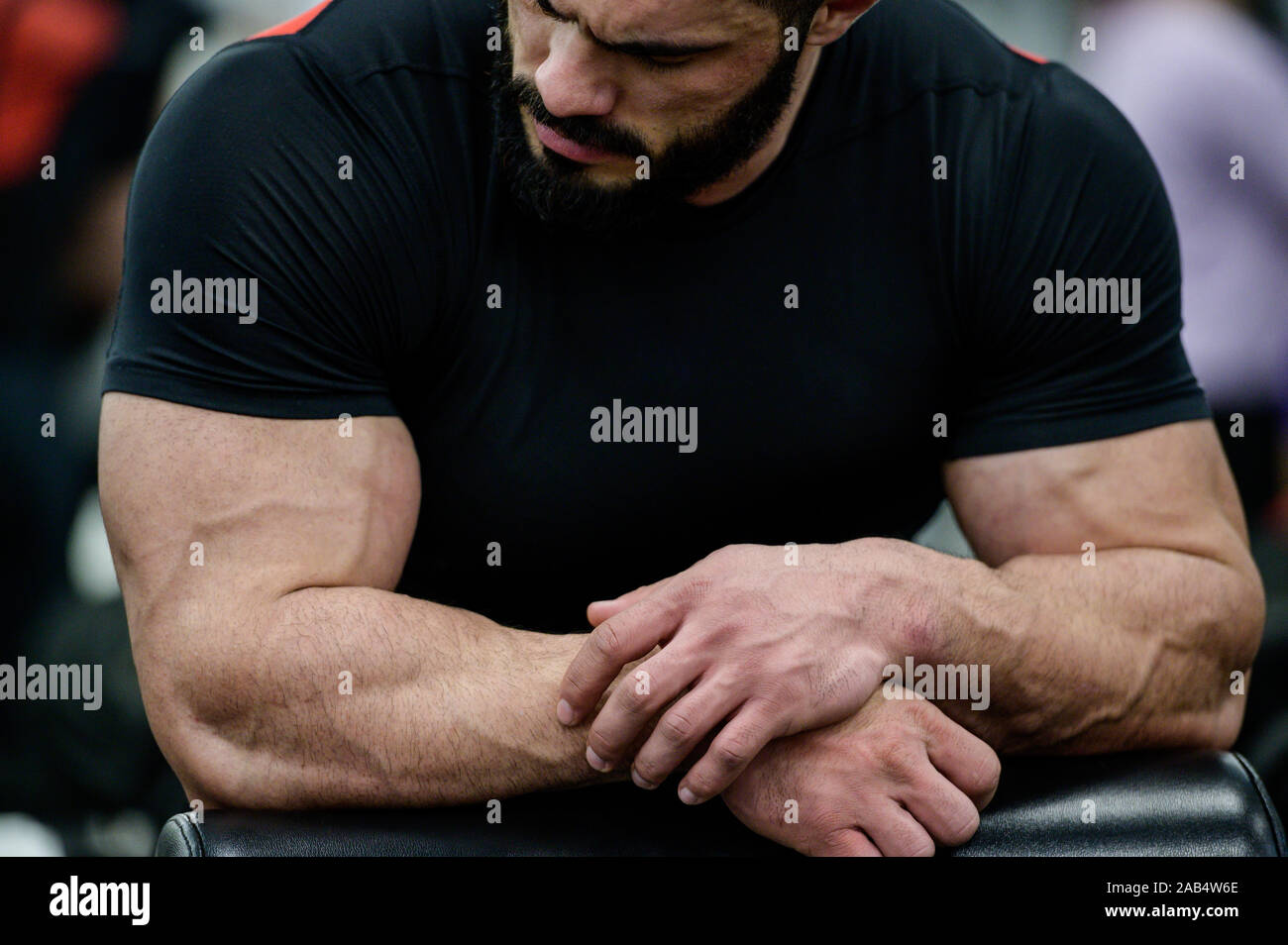 Sport concentrazione mentale concetto di giovani mucle forte carino maschio con la barba che indossa abiti neri appoggiata su simulatore in palestra Athletic Foto Stock