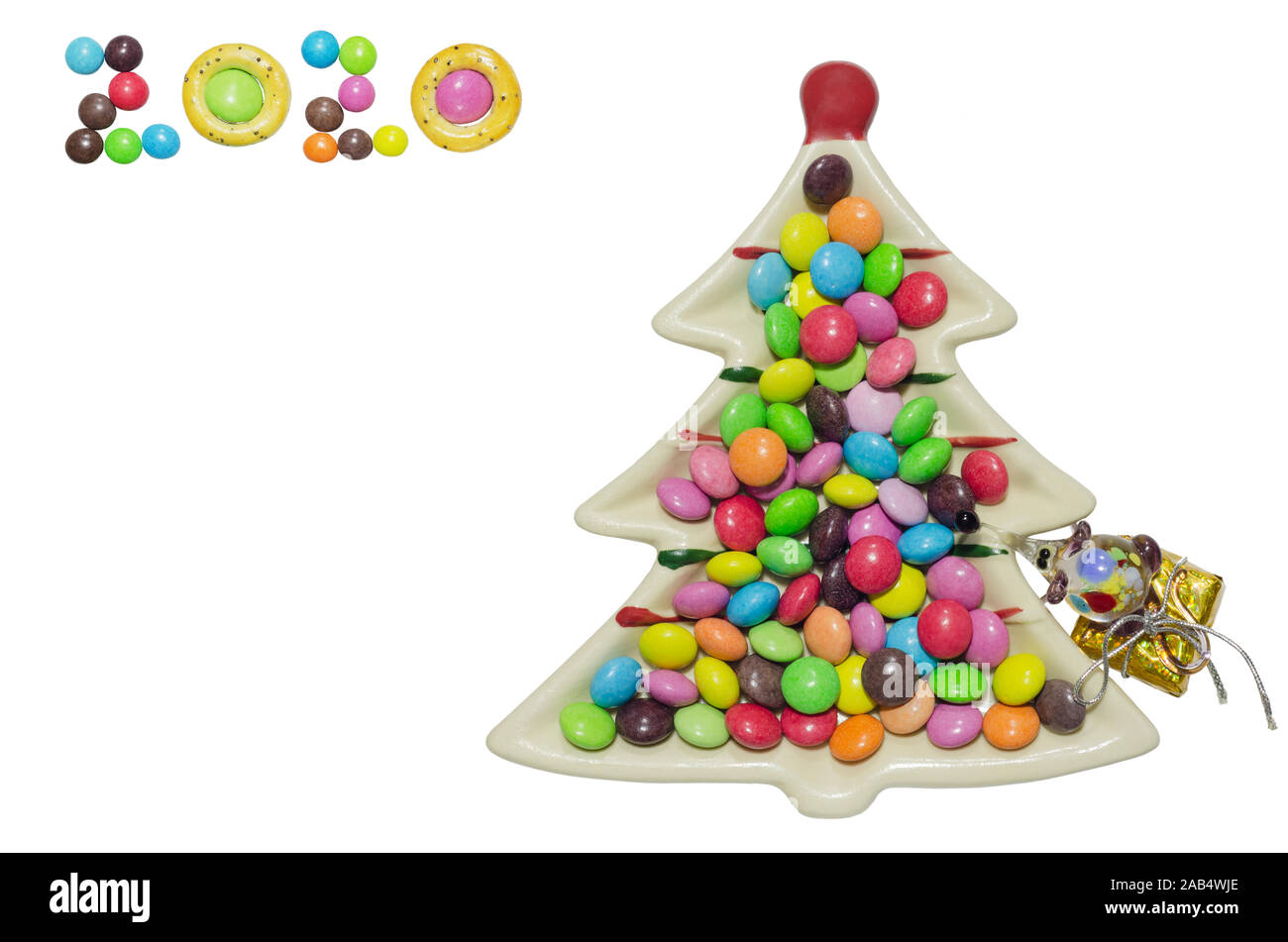 Gruppo di caramelle al cioccolato colorate in un piatto a forma di albero di Natale. Isolato su sfondo bianco, vista dall'alto Foto Stock