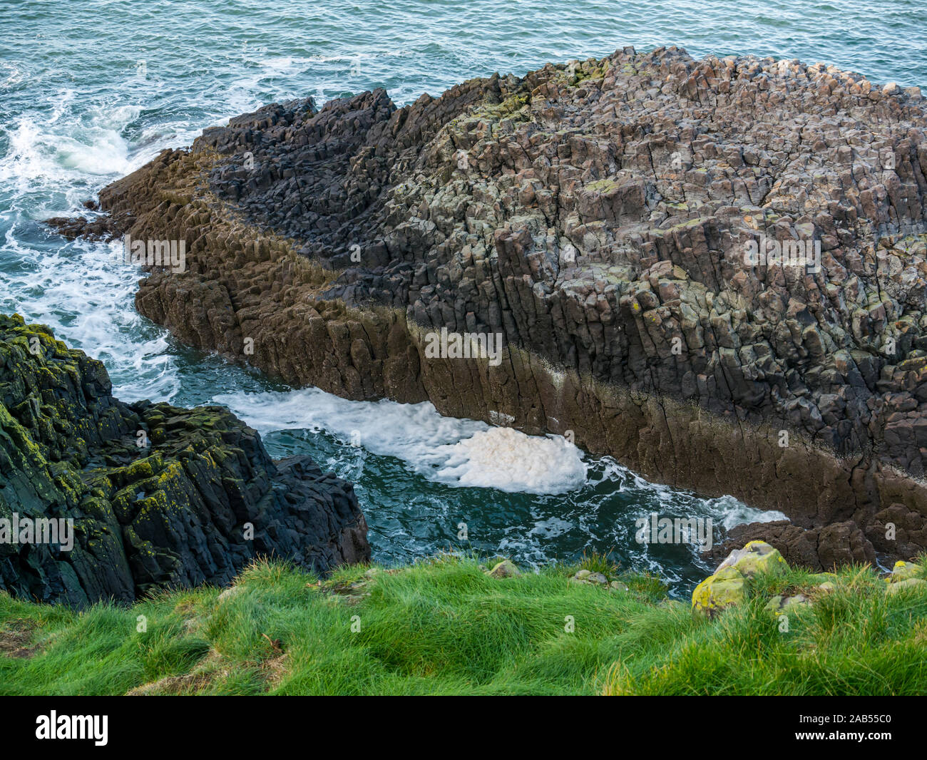 La schiuma, la schiuma e le onde di basalto sulla spiaggia rocciosa di ingresso, Isola di agnello, Firth of Forth, Scotland, Regno Unito Foto Stock