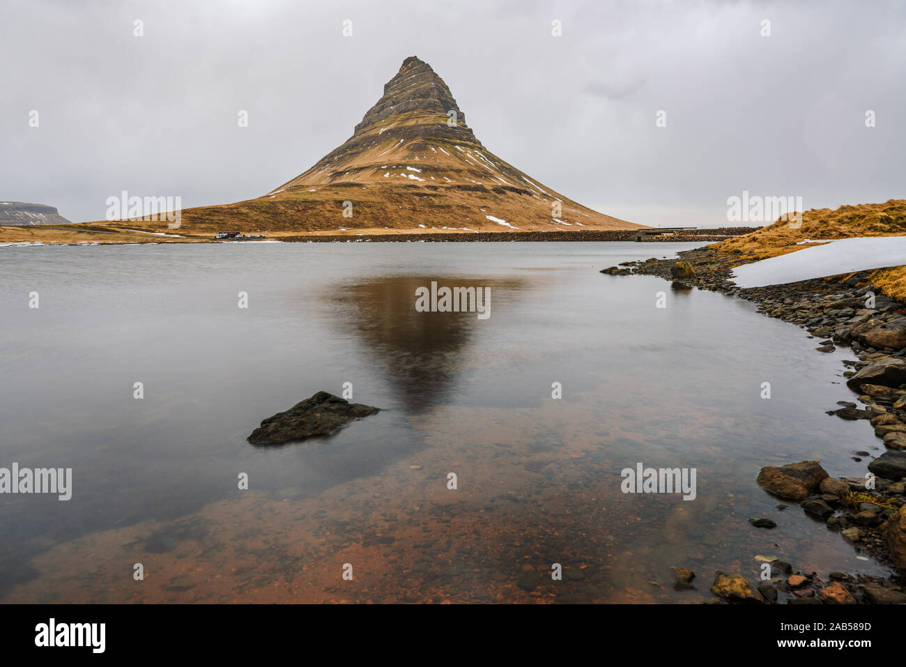 Famosa montagna con cascate in Islanda, kirkjufell, inverno in Islanda, ghiaccio e neve, riflessioni, giallo Erba, natura, ic Foto Stock