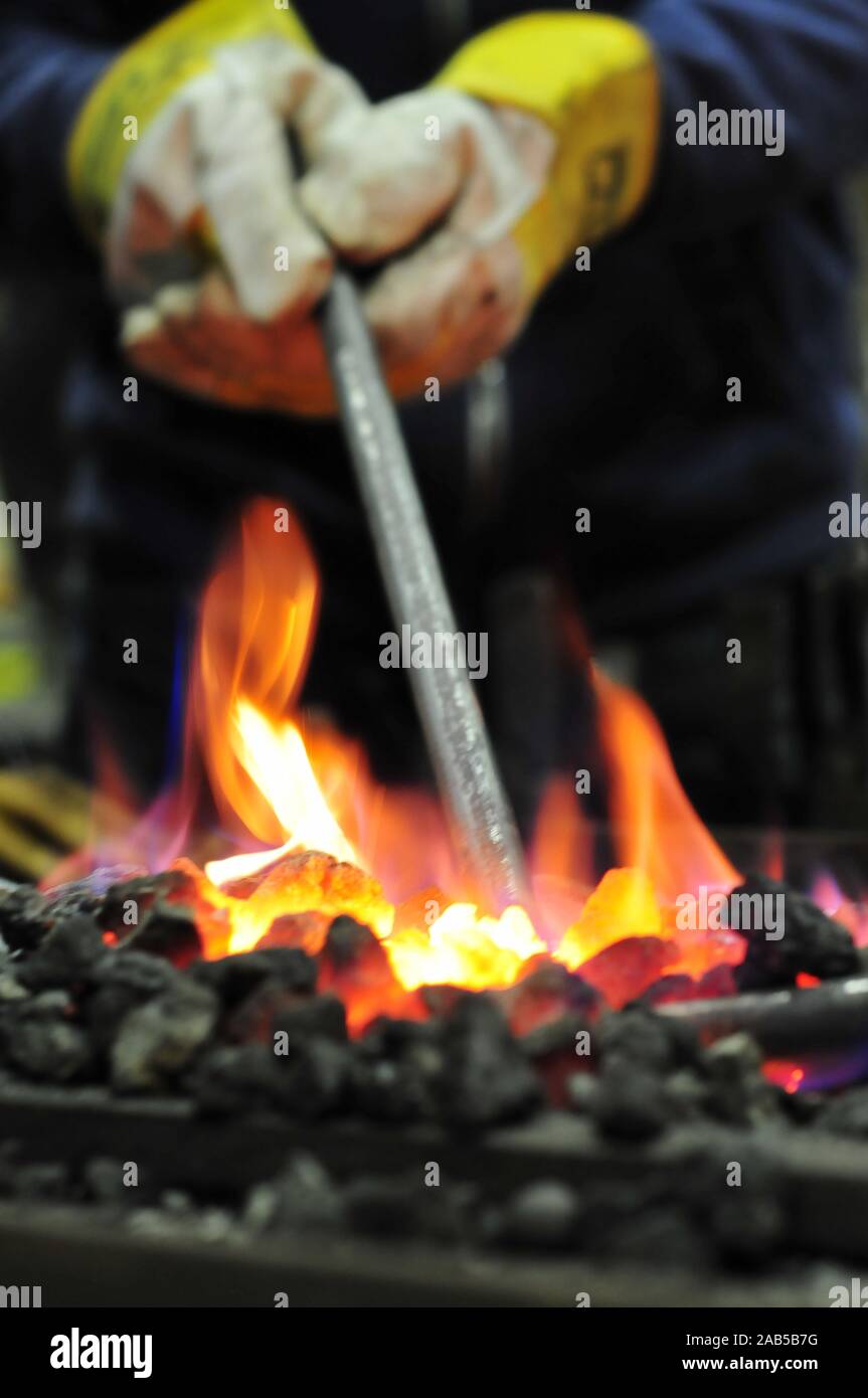 Ferro incandescente in carbone incandescente in una fucina mentre la forgiatura Foto Stock