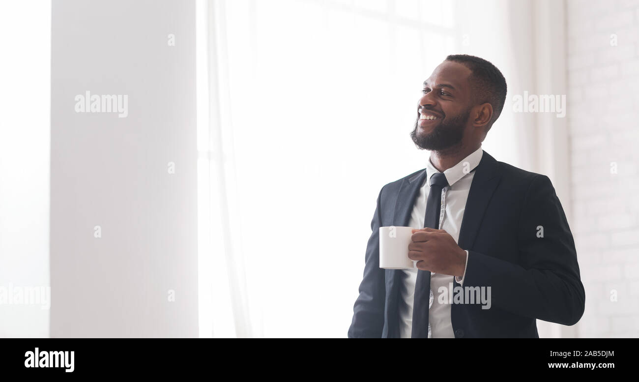 Eccitato giovane imprenditore nero godendo di caffè, felice con il suo lavoro Foto Stock