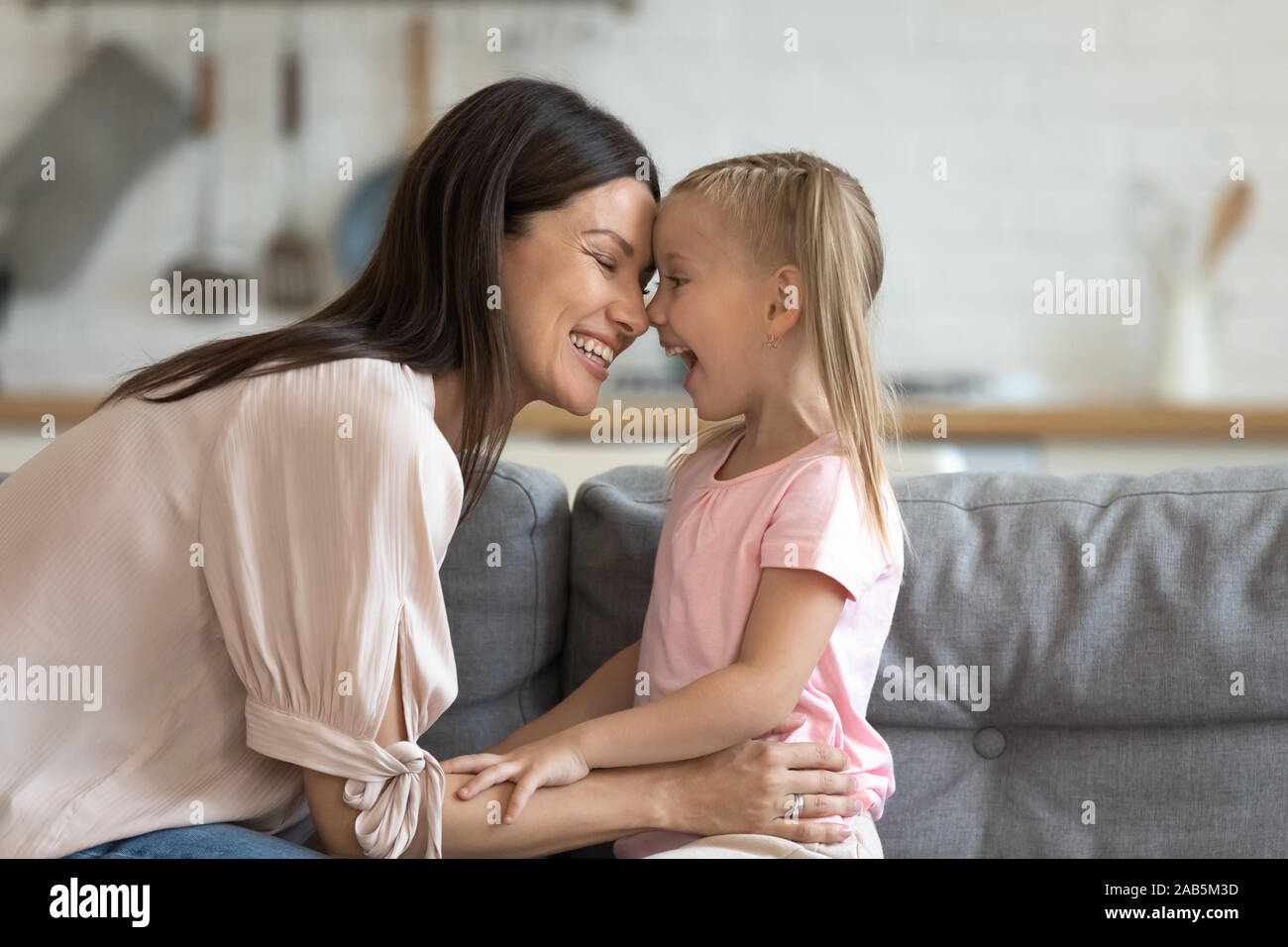 Felice madre divertendosi con cute kid figlia sul divano Foto Stock