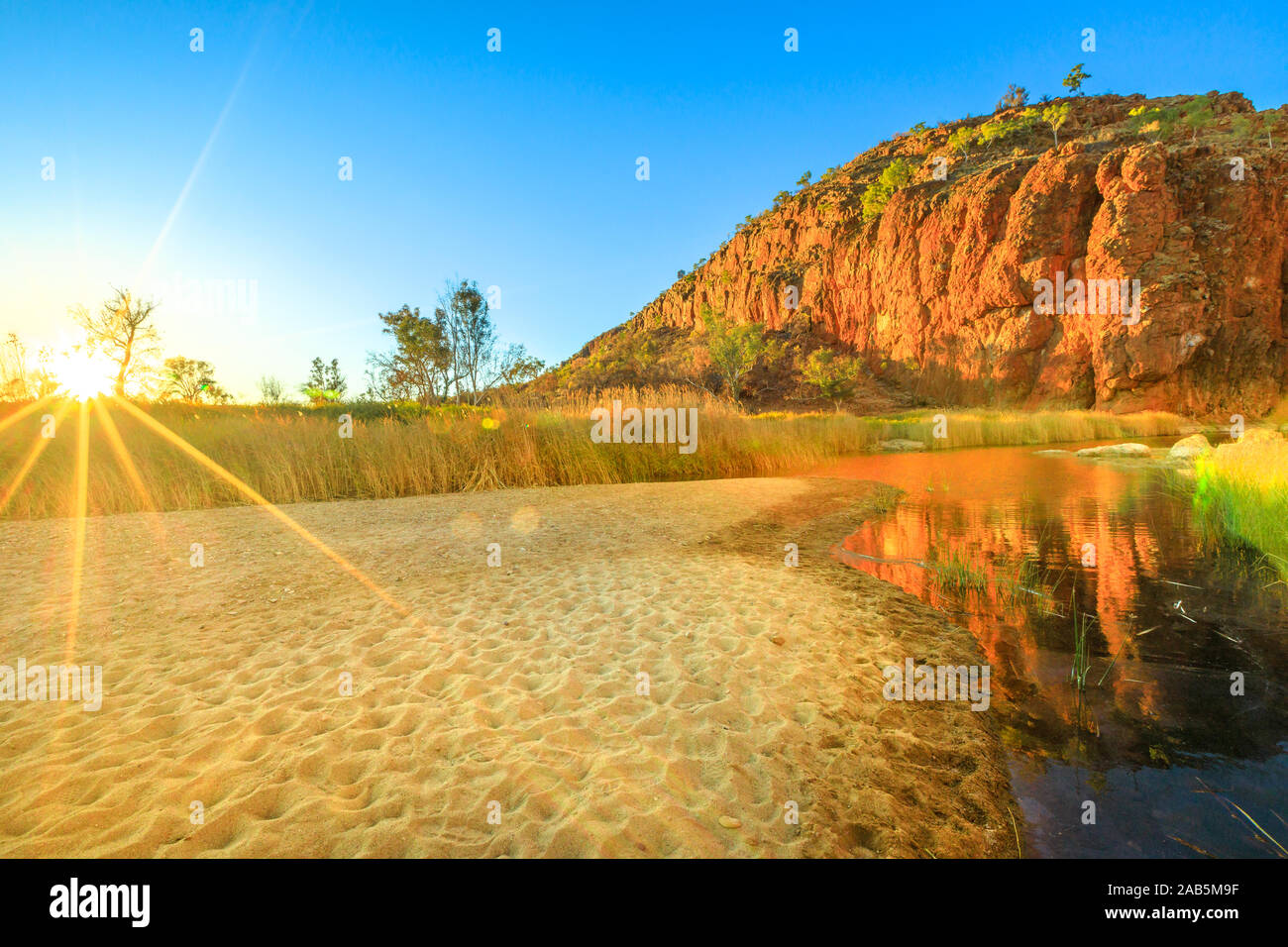 Sunrise a Glen Helen Gorge. West MacDonnell Ranges refleted su un fiume nel Territorio del Nord, Centrale Outback australiano. Scenic red rock Foto Stock