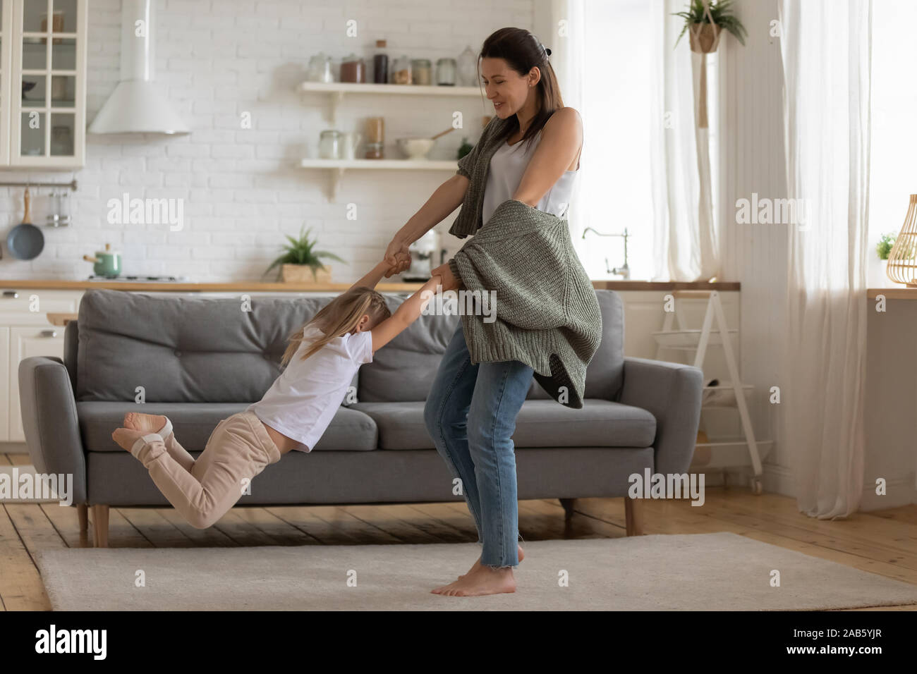 Felice madre di filatura di sollevamento bambino figlia dancing in cucina moderna Foto Stock