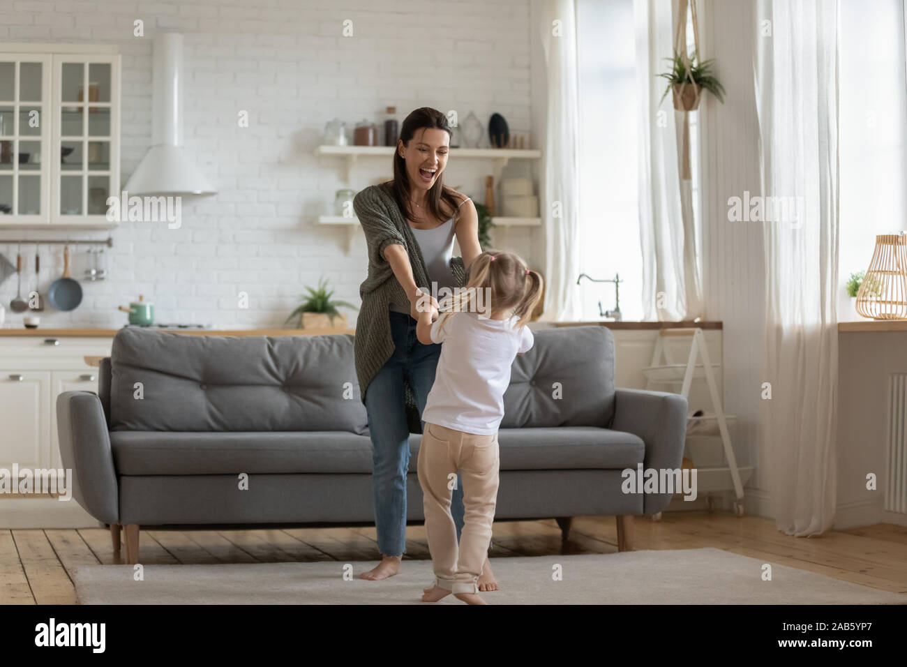 Carefree kid girl divertendosi con la madre dancing in cucina Foto Stock