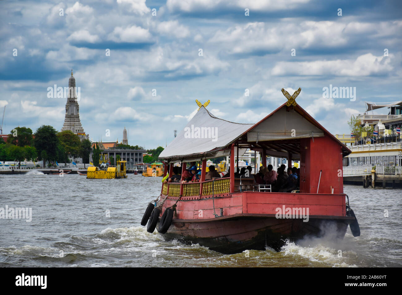 Bangkok, Thailandia .11.24.2019: un rosso tradizionale in legno barca con tourist è attraversando il Fiume Chao Phraya verso il famoso e sorprendente Wat Arun un Foto Stock