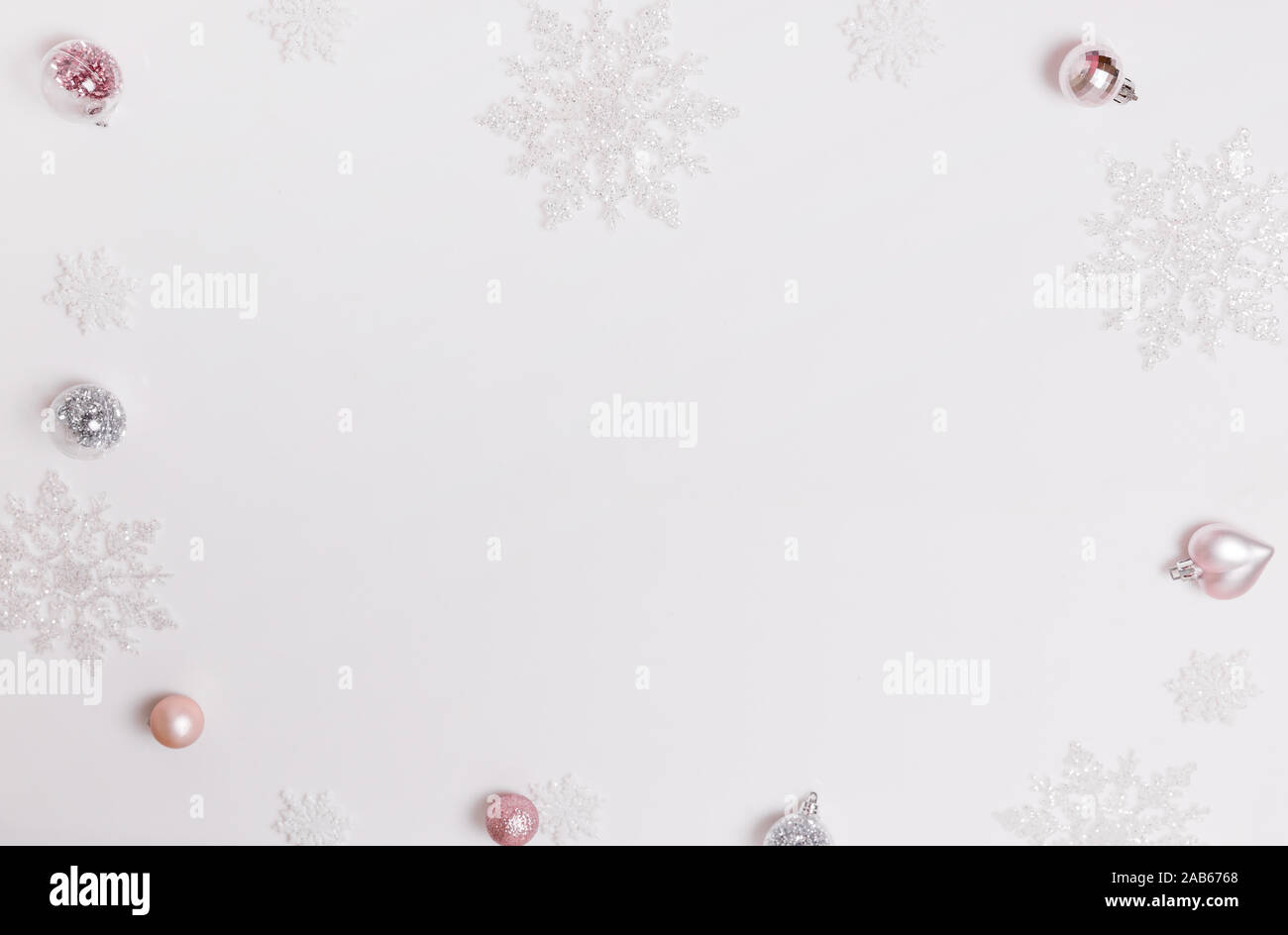 Composizione di natale. Cornice fatta di palline e fiocchi di neve pastello su sfondo grigio. Foto Stock