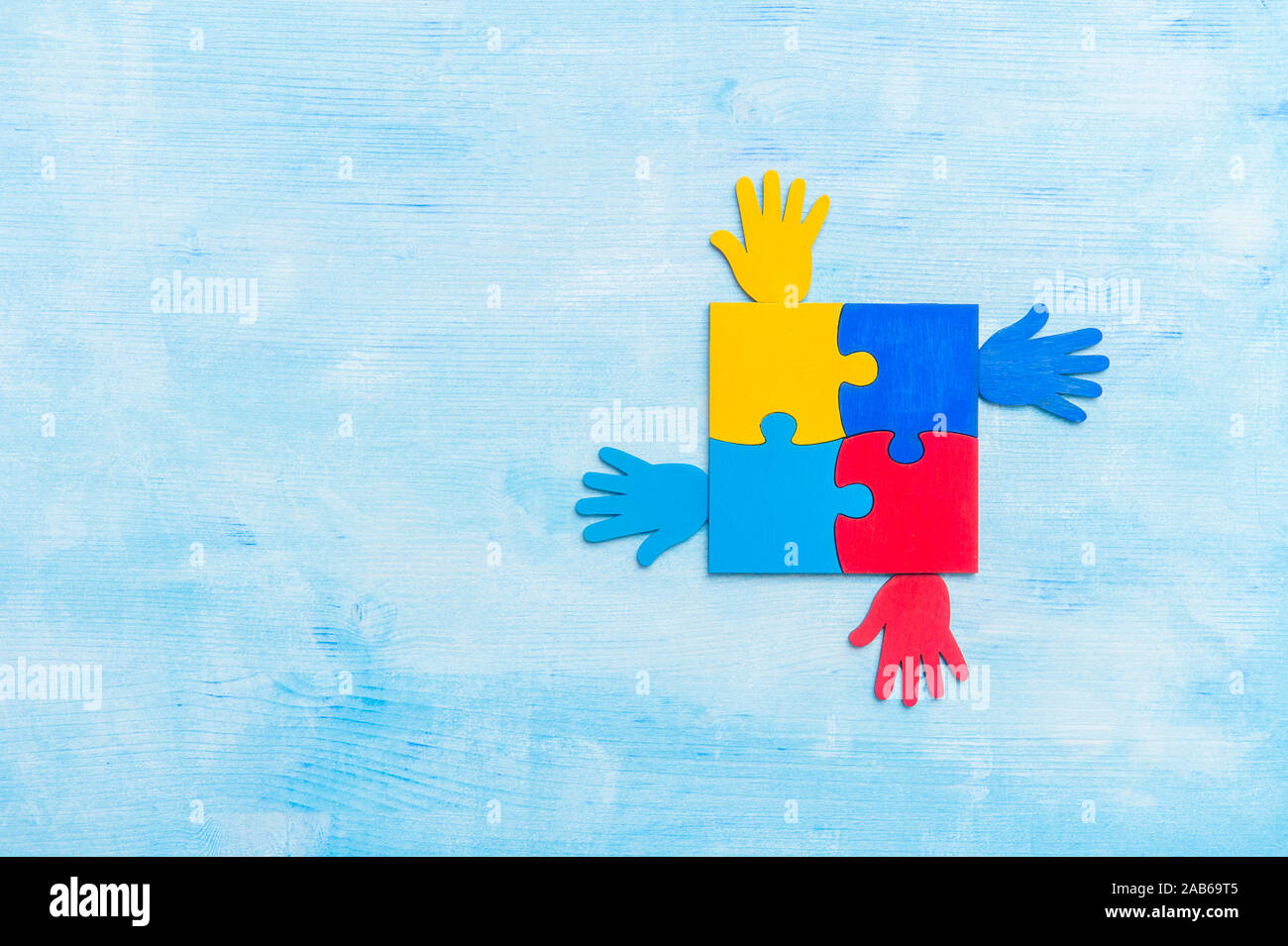 Colorfull puzzle pezzo e mani su sfondo blu. Mondo autismo Consapevolezza Giorno di concetto Foto Stock