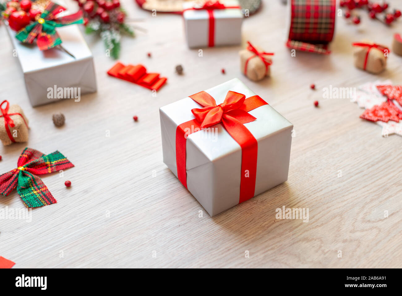 Dono sul tavolo circondato da addobbi e regali. Concetto di preparazione di Natale di doni. Close-up. Foto Stock