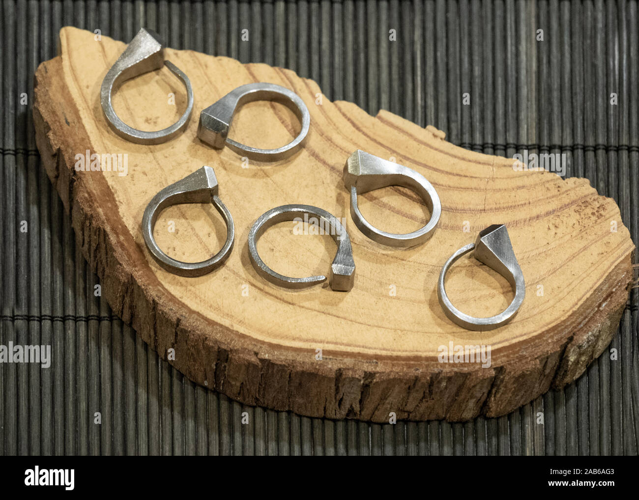 Unghie ricurve trasformato in anelli, esposta su un piatto di legno Foto Stock