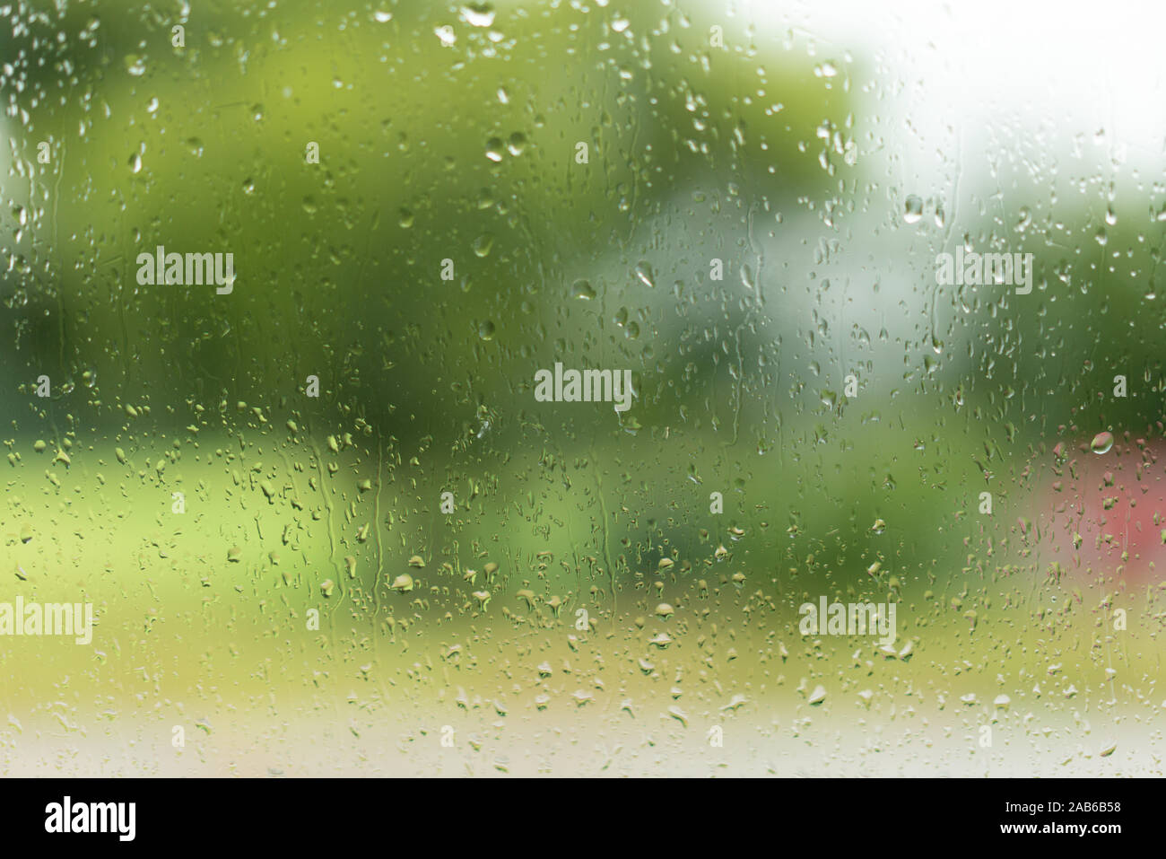 Vista attraverso una finestra con le gocce di pioggia, unsharp colori in background Foto Stock