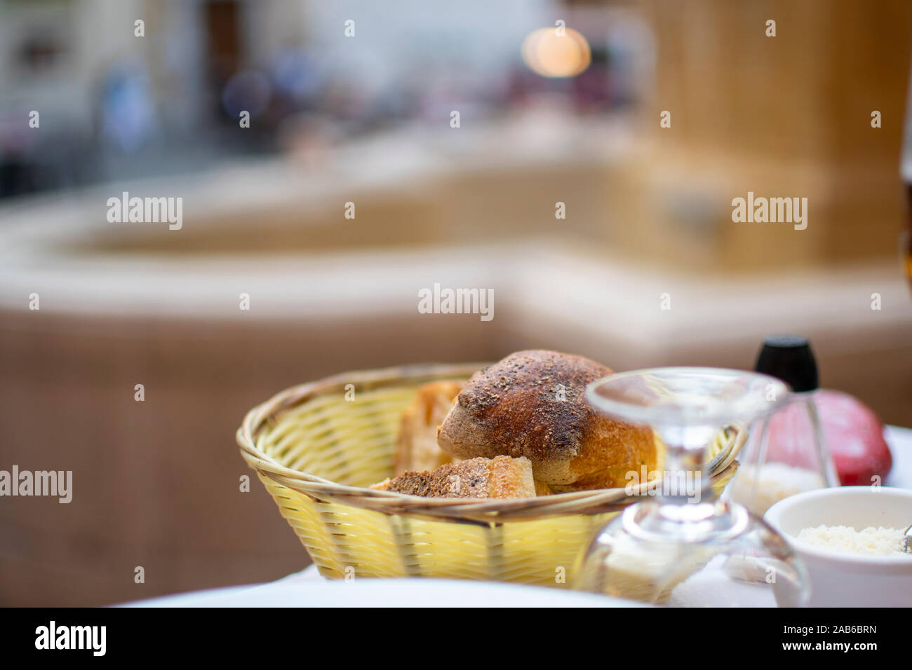 Un cesto di pane e panini su un patio con tavolo in una piazza di fronte a una fontana a Nizza Francia. Foto Stock