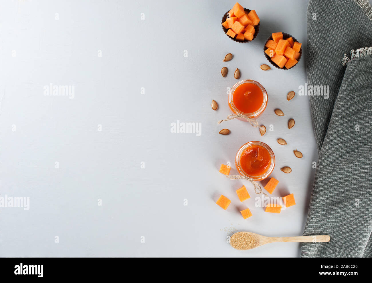 Fresco marmellata di zucca in vasi su sfondo grigio decorate con i semi di zucca e zucchero di canna. In autunno le ricette di una zucca. Cibo sano concetto Foto Stock