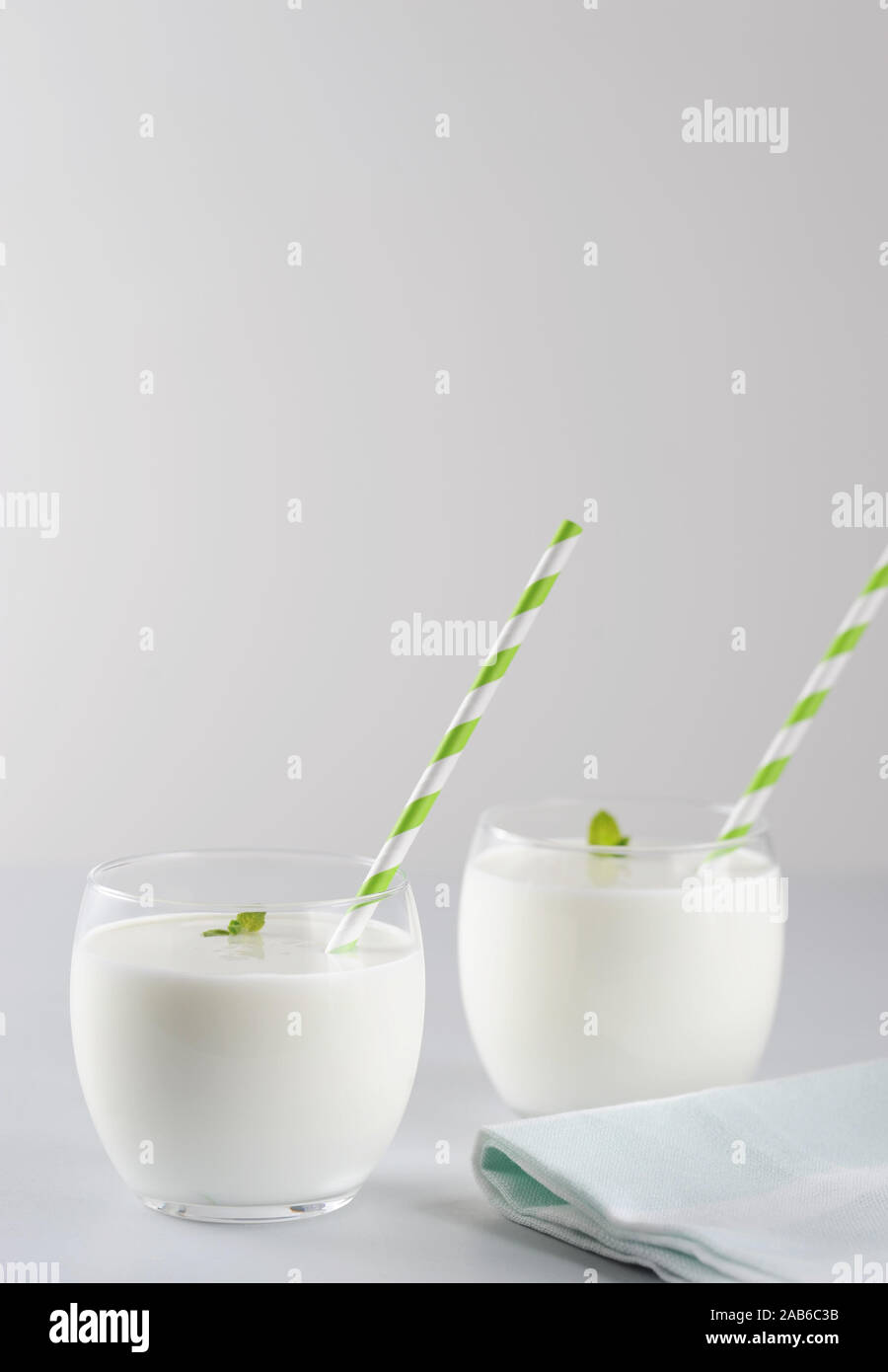Ayran, yogurt drink (kefir, lassi) con foglia di menta in due bicchieri. Rinfrescanti drink freddo.orientamento verticale con spazio copia,fuoco selettivo. Foto Stock