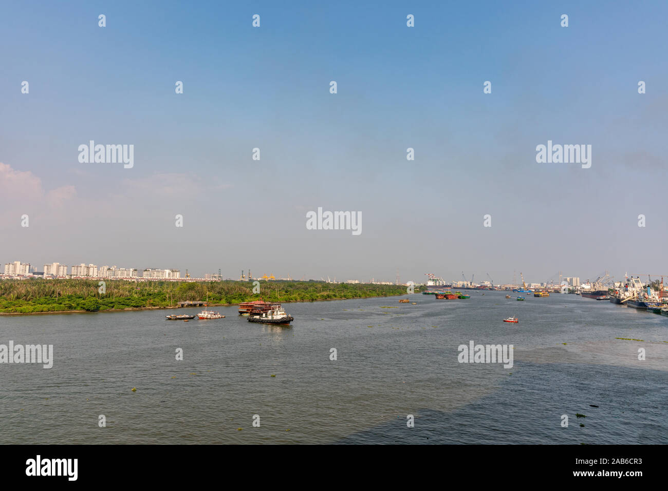 La città di Ho Chi Minh, Vietnam - Marzo 13, 2019: Guardando downriver al tramonto su grigio-blu canzone Sai Gon River da downtown: barche, cintura verde, blu cielo, t Foto Stock