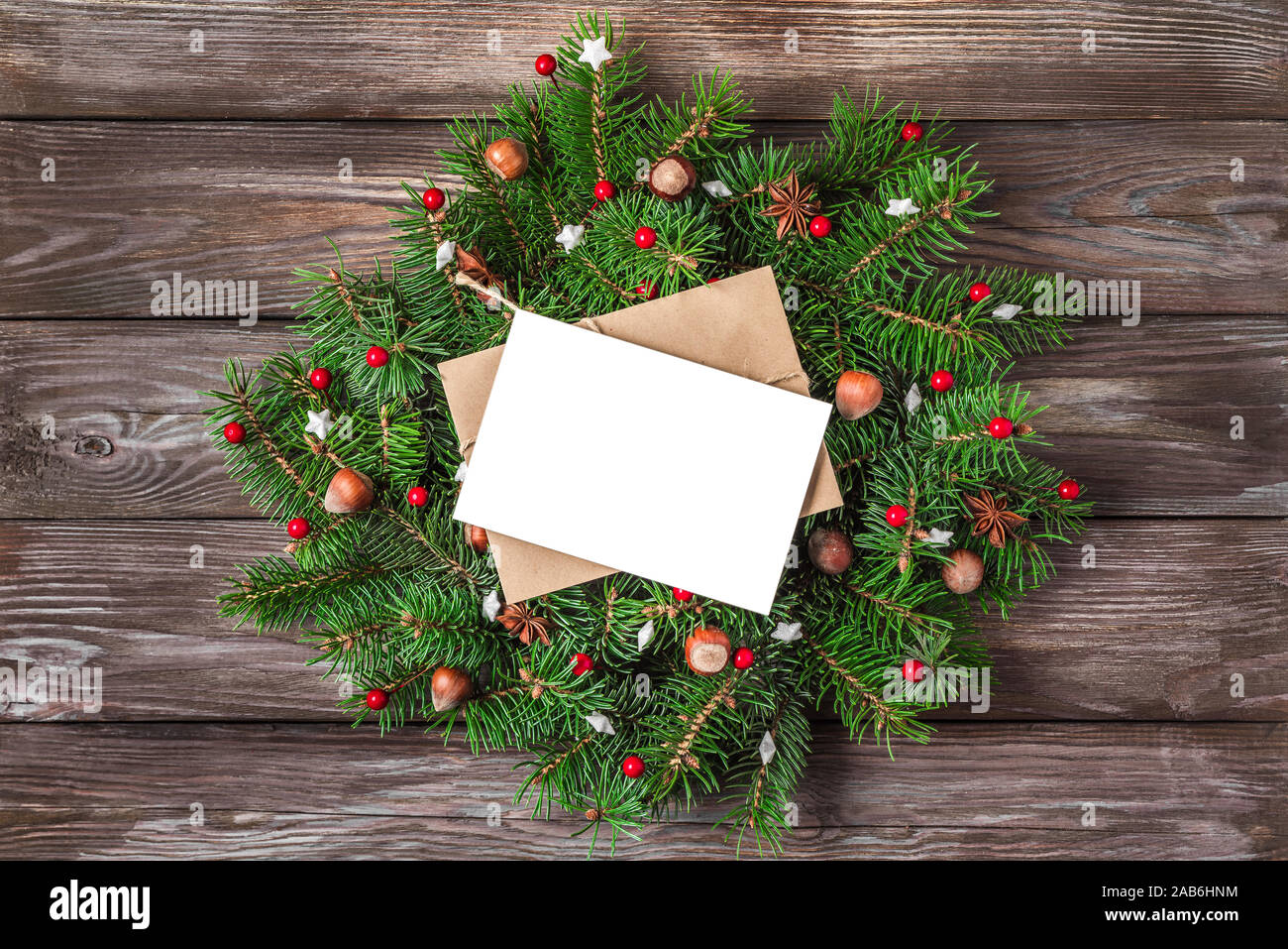 Auguri di Natale carta con la ghirlanda di Natale con holiday decorazione su legno rustico sfondo. flat laici. vista superiore Foto Stock