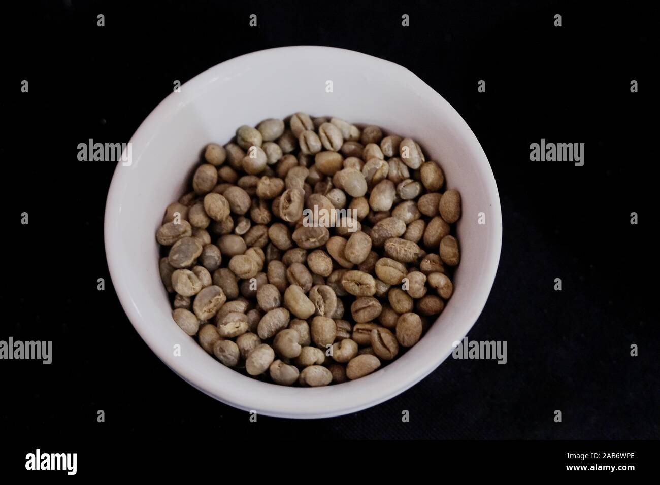 Piatto di ceramica contenente peaberry non torrefatto Caffè in grani. Originati dal solo pochi agricoltori in Kenya i semi sono venduti a un prezzo premium. Foto Stock