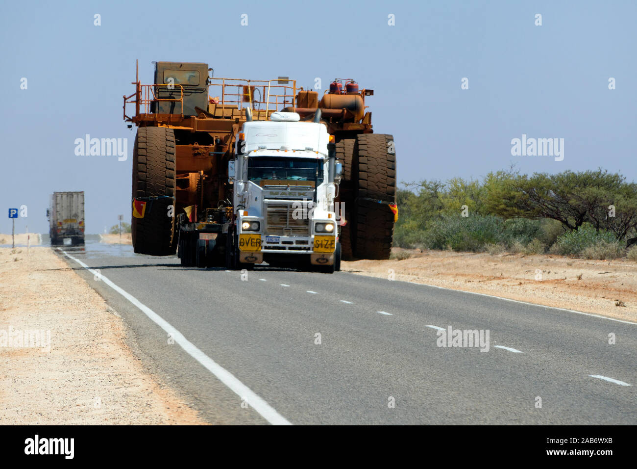 Over Size di trasporto su strada di un autocarro con cassone ribaltabile su un molto caldo outback autostrada con calore sfarfallare, Australia occidentale Foto Stock