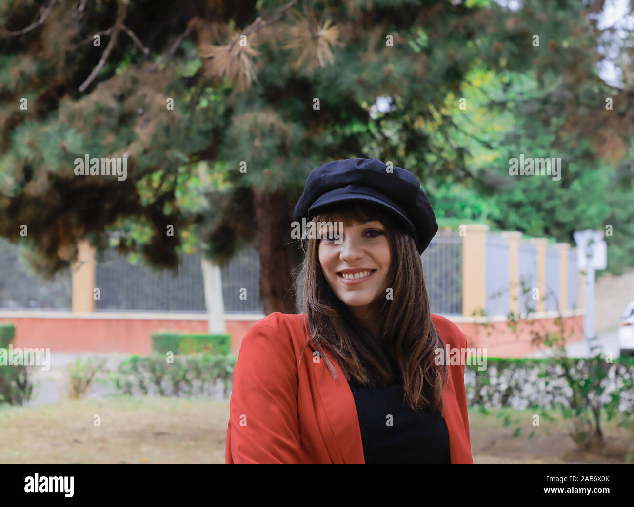 Bella giovane donna con giacca rossa e il cappuccio nero, godendo nel parco Foto Stock