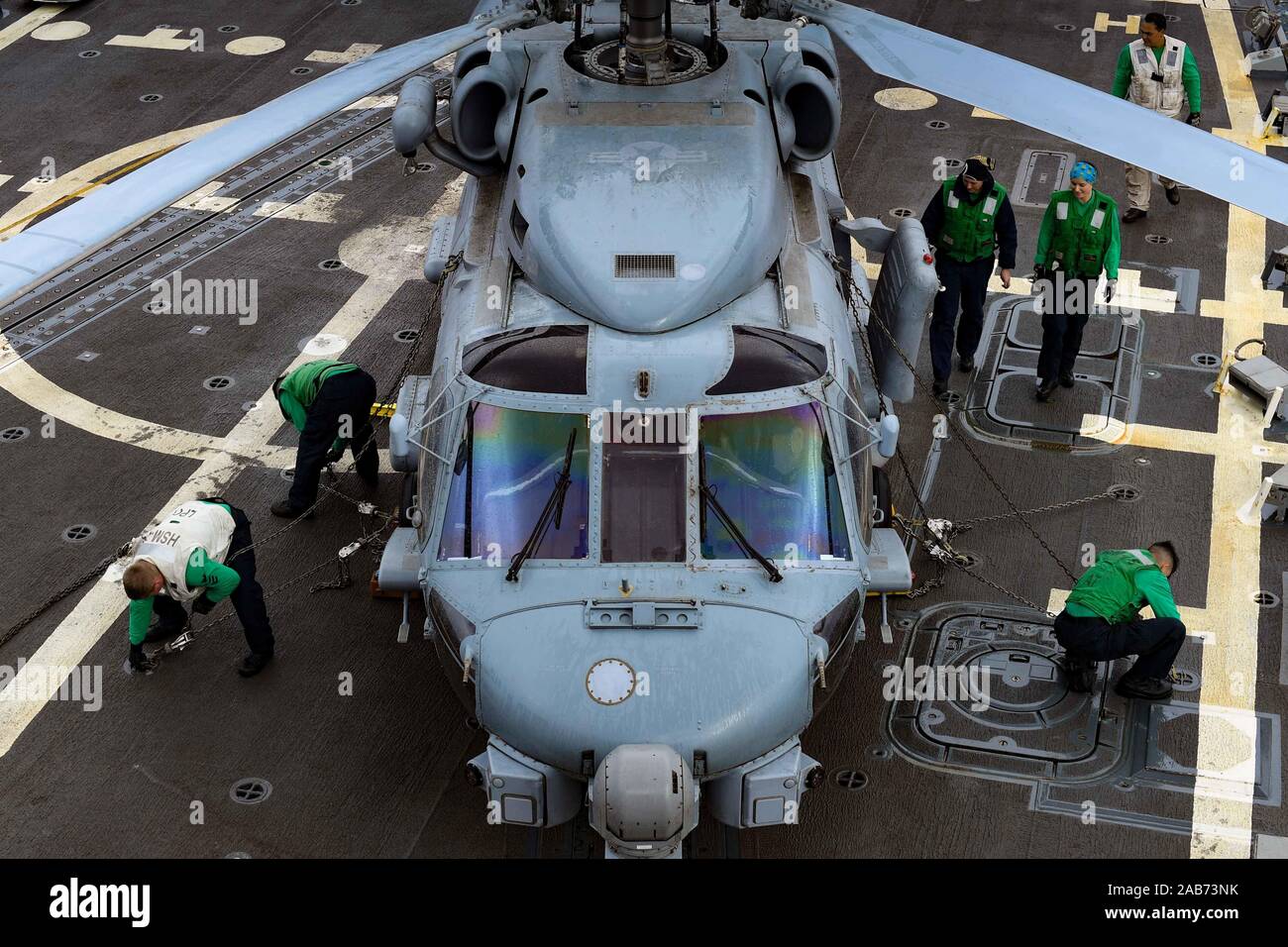 Oceano Pacifico (nov. 20, 2019) marinai una catena MH-60R Sea Hawk, assegnato al "Wolf Pack" di elicottero Maritime Strike Squadron (HSM) 75, per il ponte di volo della Arleigh Burke-class guidato-missile destroyer USS Pinckney (DDG) 91 nov. 20, 2019. Pinckney è in corso conducendo la formazione di routine nell'Oceano Pacifico orientale. (U.S. Foto di Marina di Massa lo specialista di comunicazione di terza classe Erick A. Parsons) Foto Stock