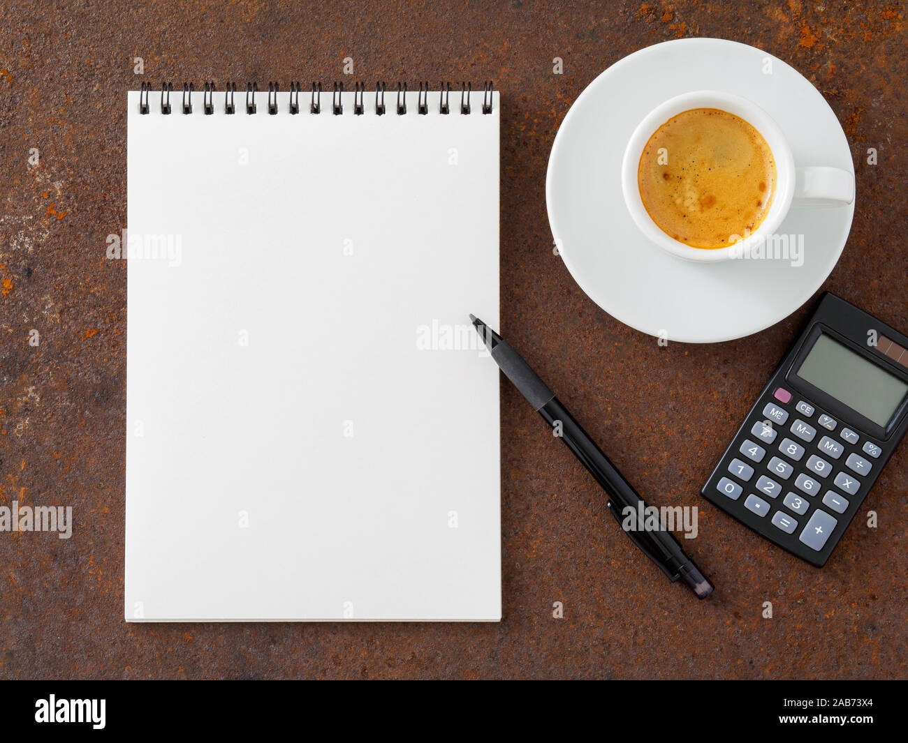Pulire il foglio bianco in un aperto a spirale, pad, penna, calcolatrice e tazza di caffè sul ferro del metallo arrugginito tabella, vista dall'alto Foto Stock