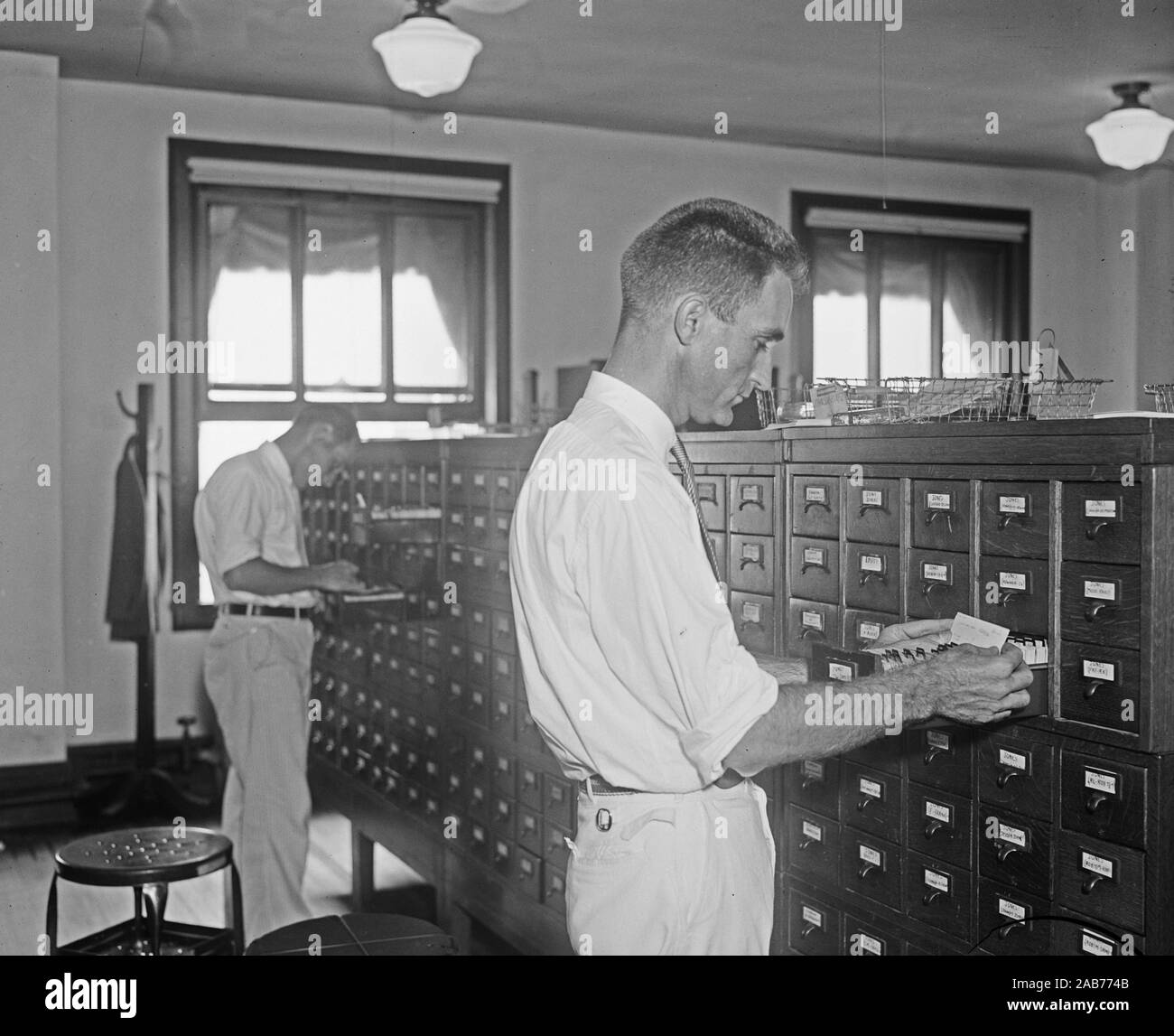 Uomo che guarda attraverso una scheda di catalogo ca. 1932 o 1933 Foto Stock