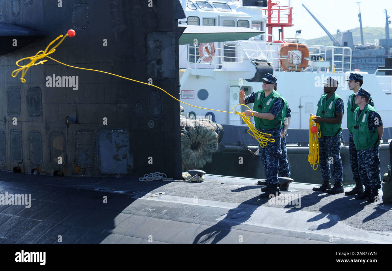 APRA HARBOR, Guam (9 aprile 2013) un marinaio a bordo del Los Angeles-class attack submarine USS Jacksonville (SSN 699) genera una linea di ricevimento al molo come Jacksonville arriva a condurre la libertà e la manutenzione. Foto Stock