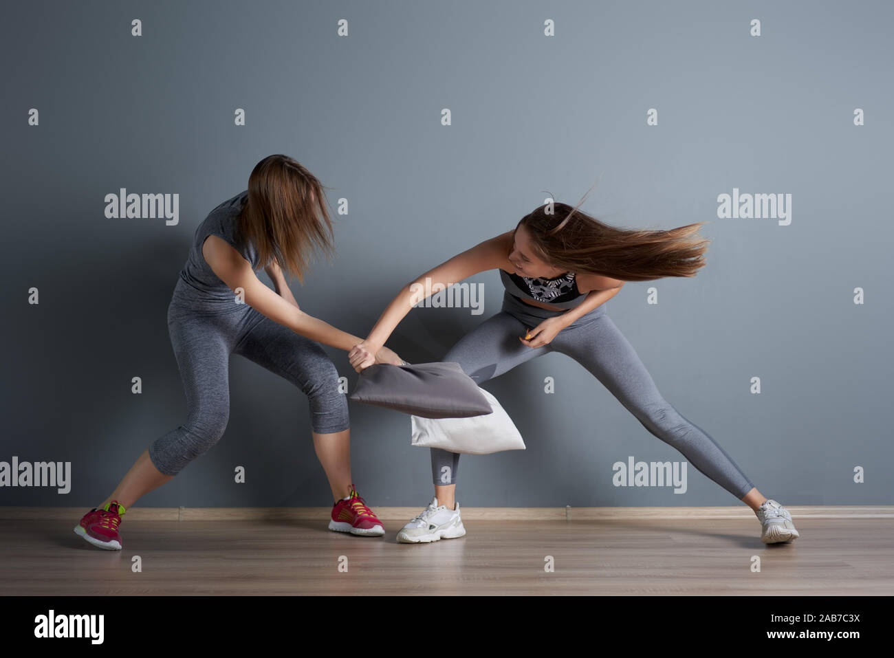 Due ragazze sport lotta cuscini in palestra contro il muro grigio Foto  stock - Alamy