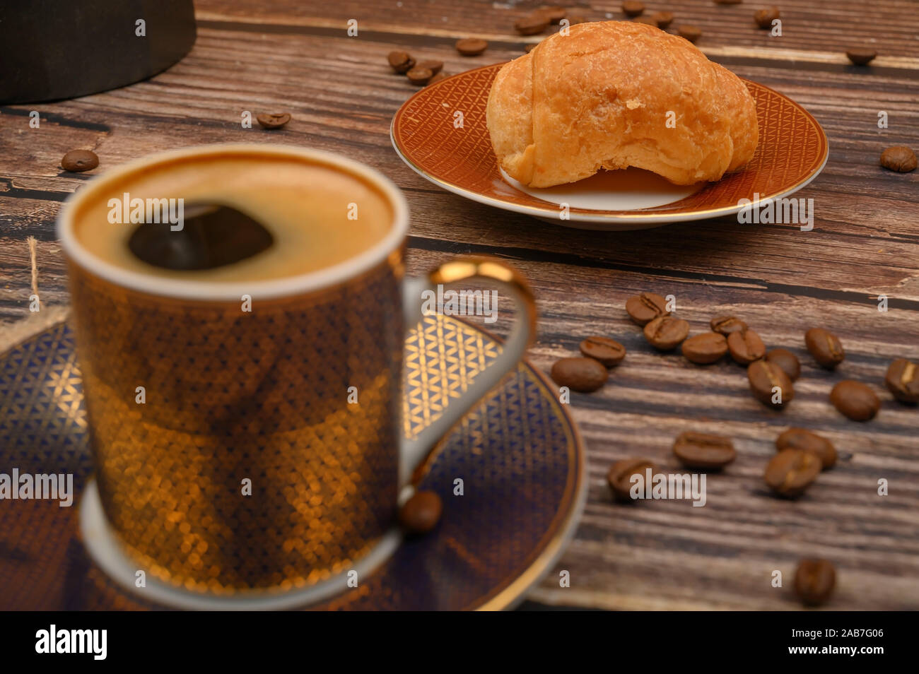 Tazza da caffè, croissant e caffè in grani su sfondo di legno. Close up Foto Stock