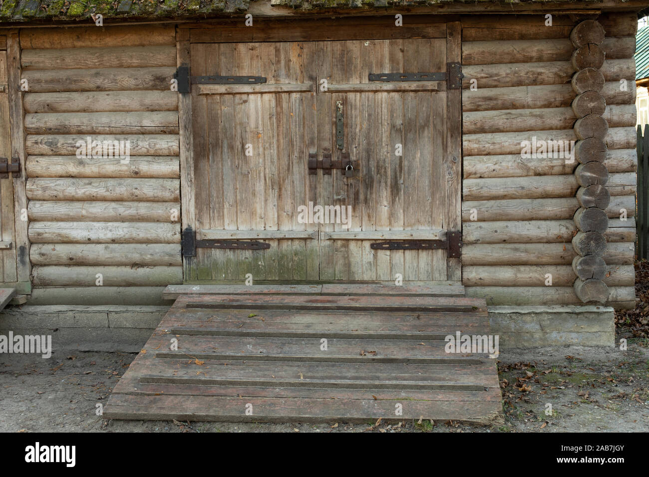 Il vecchio fienile in legno porta con cerniere in metallo e una serratura. Un vecchio fienile rurale, non-edificio residenziale nel villaggio. Foto Stock
