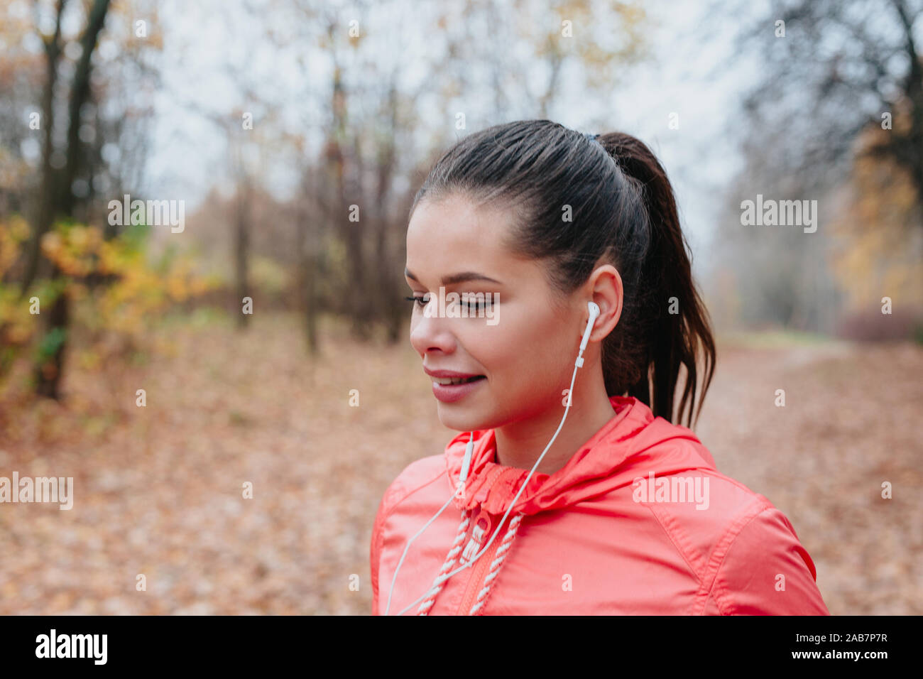 Sporty giovane donna in esecuzione nel parco e ascolto di musica. Stile di vita sportiva. Foto Stock