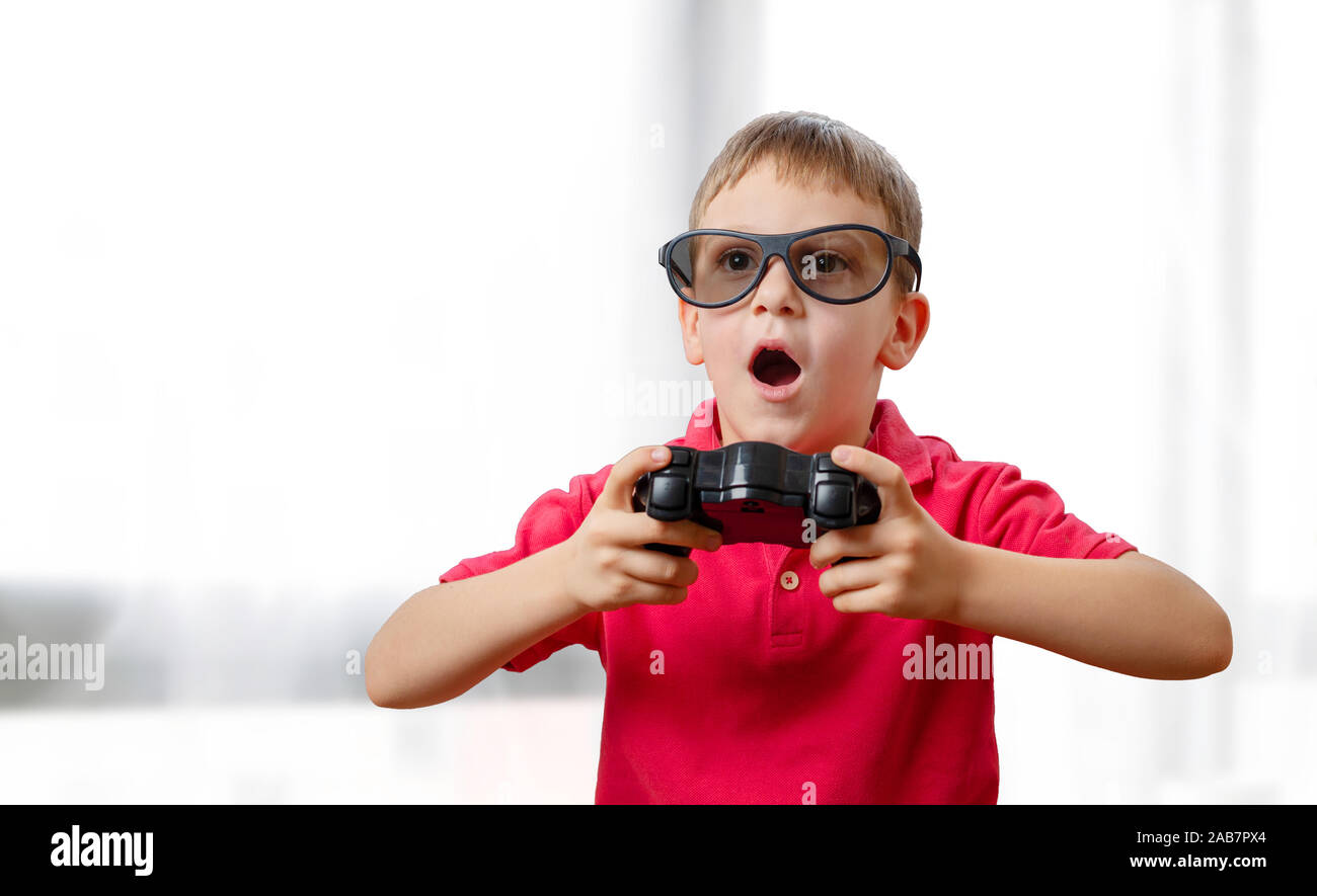Il bambino gioca con una pulsantiera e occhiali 3d. La sua bocca leggermente aperta con entusiasmo. Foto Stock