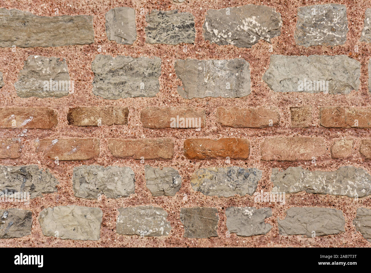 Grigio a muro di pietra texture con red fire mattoni nel mezzo. Incollato con rosso di cemento colorato. Foto Stock