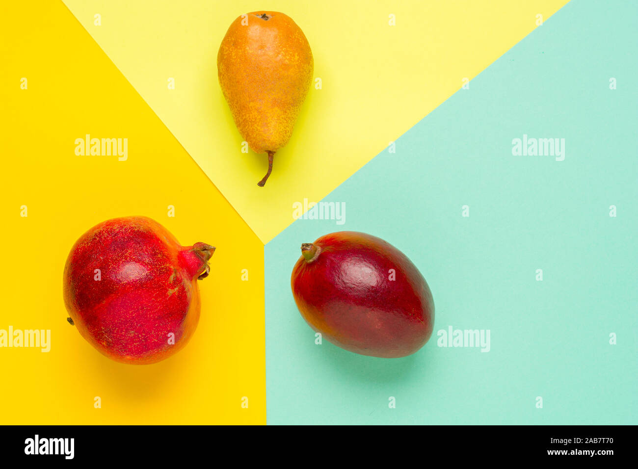 Layout creativo fatto di frutti. Lay piatto. Pera, mango e melograno su sfondo colorato con copia spazio. Foto Stock