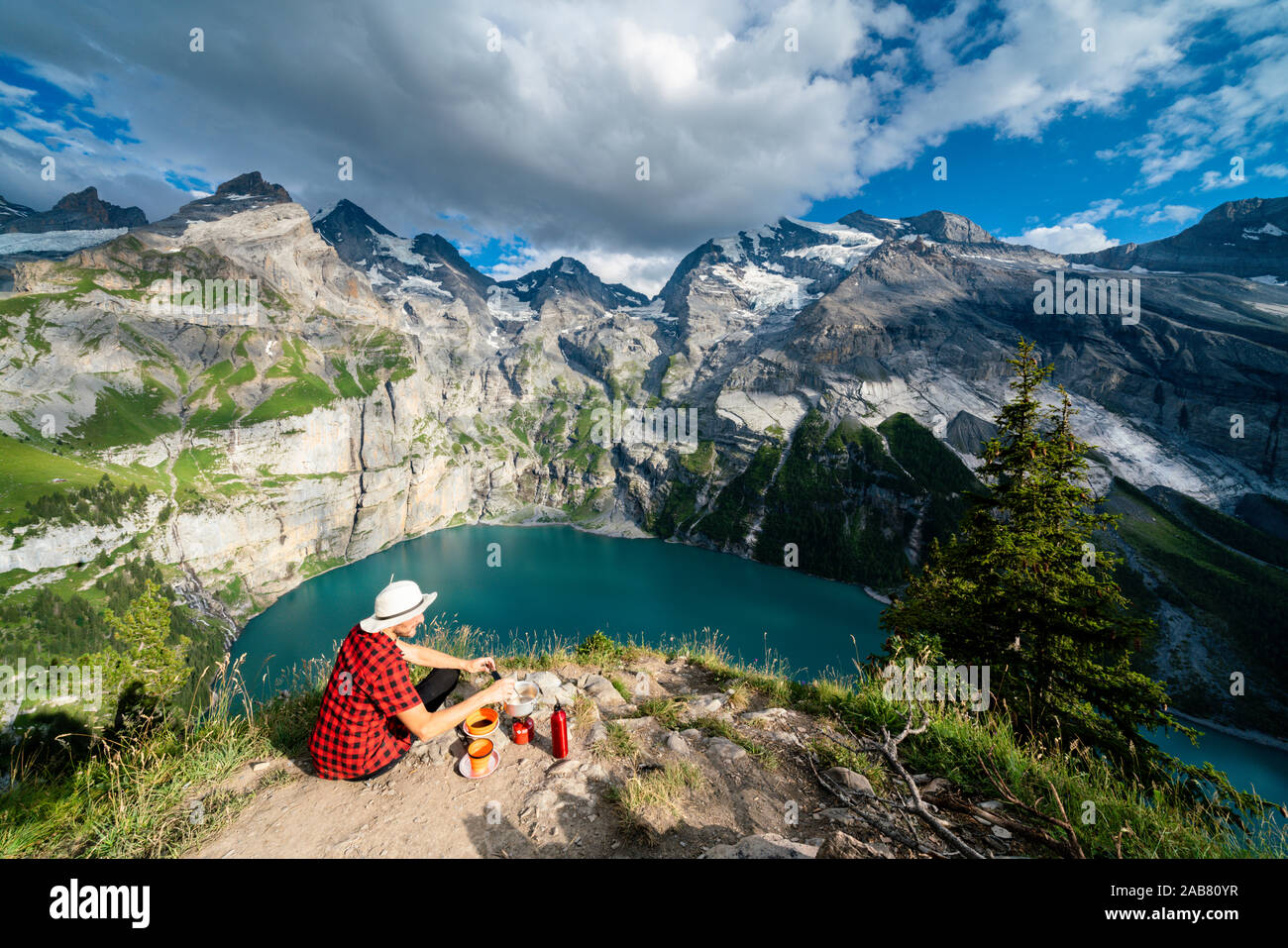 Escursionista la cottura di cibo sul fornello da campeggio in alto sopra il lago Oeschinensee, Oberland bernese, Kandersteg, cantone di Berna, Svizzera, Europa Foto Stock