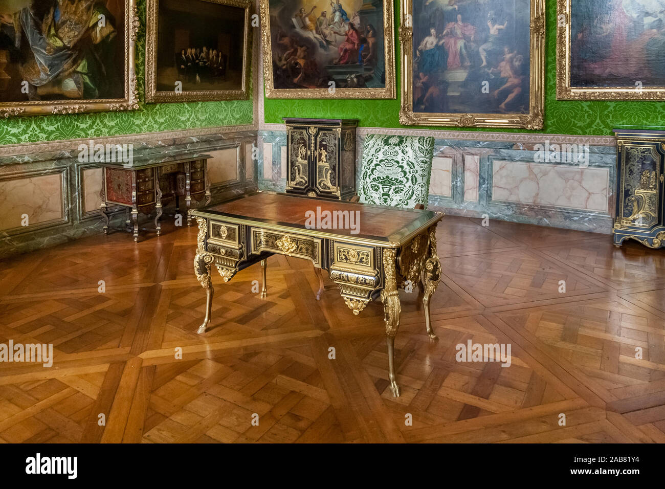 Vista ravvicinata di una bella scrivania ornata con zoccolo in piedi in una stanza con una tappezzeria verde e dipinti ad olio sulle pareti di una camera della famosa... Foto Stock