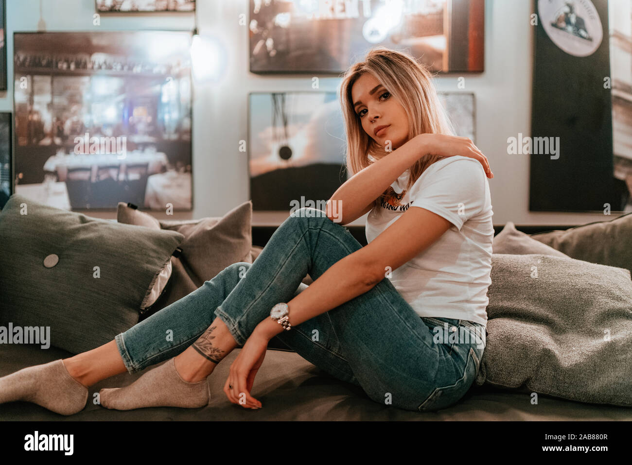 Affascinante Ritratto di giovane donna con capelli biondi, Street Style, ponendo in ambienti interni Foto Stock