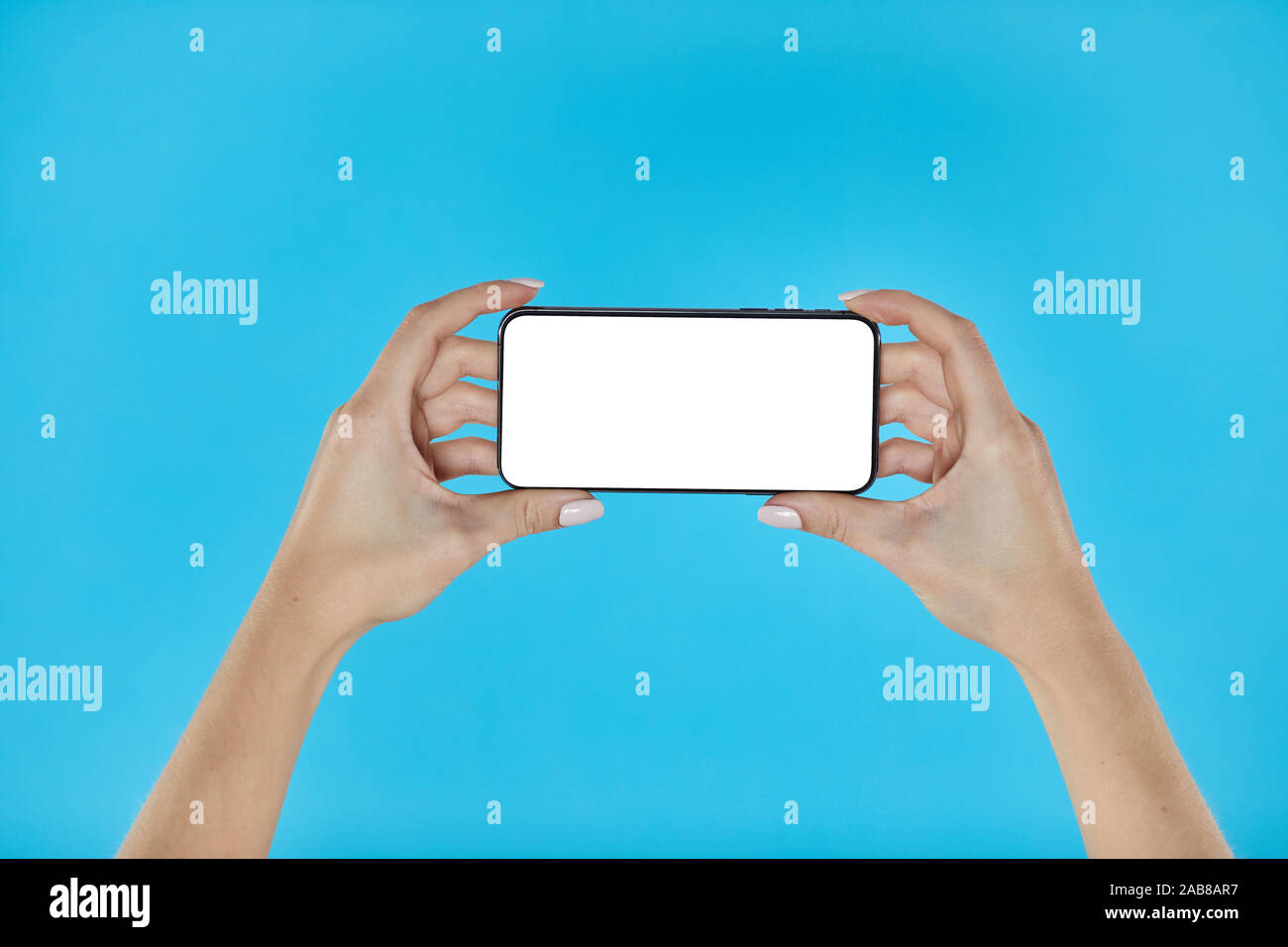 Donna mani smartphone su uno sfondo blu. Smartphone mockup con schermo bianco Foto Stock