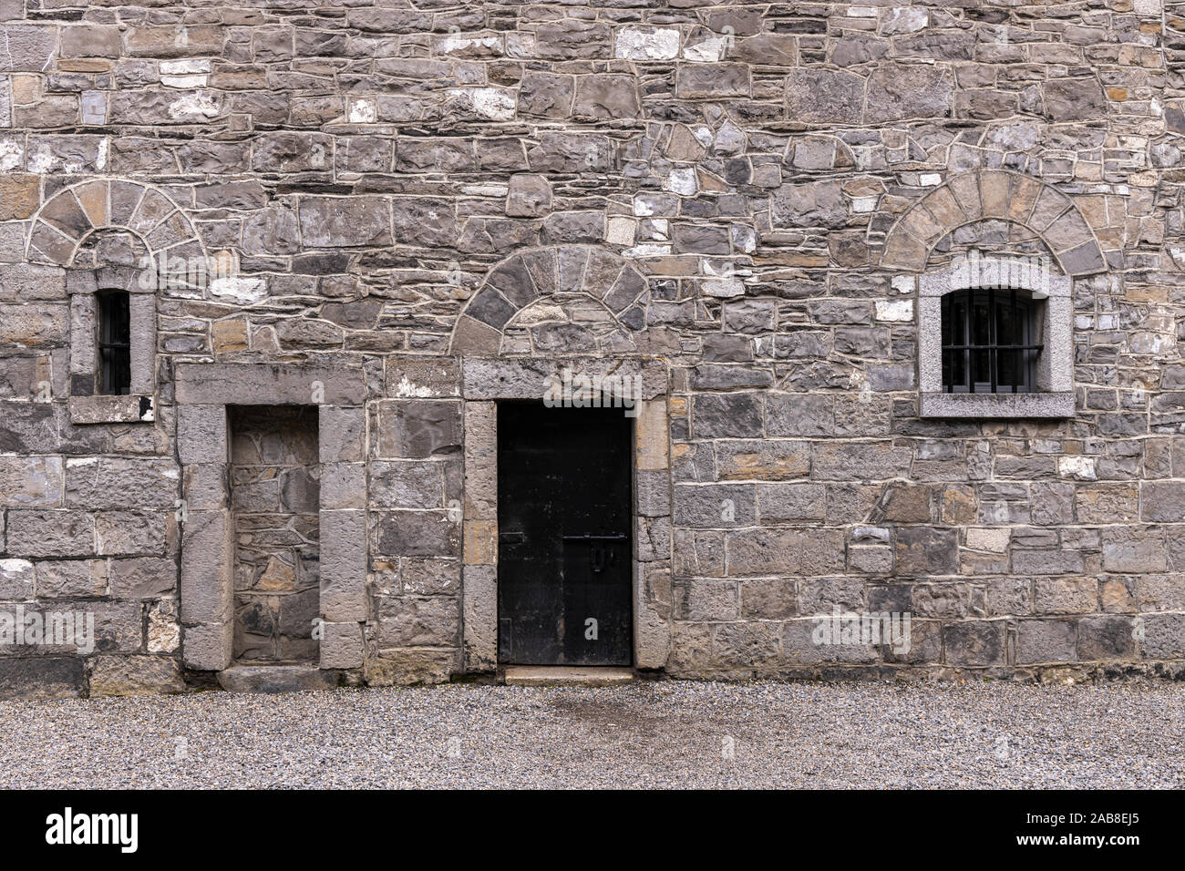 Grigio a muro di pietra con portale e finestre su un cortile interno a Kilmainham Gaol, Dublino, Irlanda Foto Stock