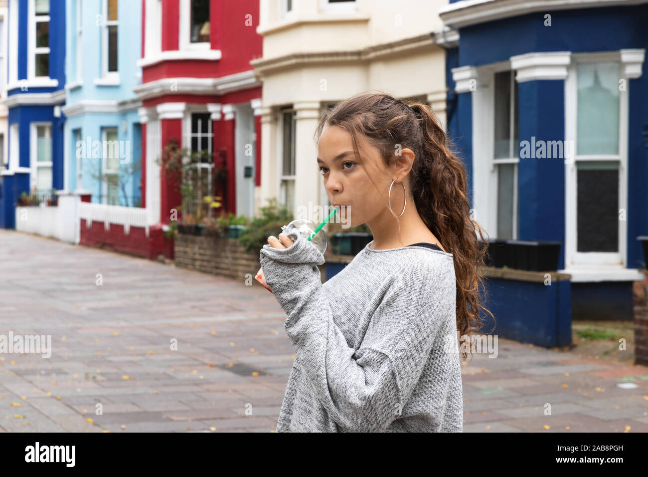 Ritratto ragazza giovane con un smoothie in mano in un contesto cittadino. Foto Stock